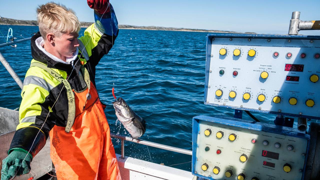 Adrian Hanssen drar en fisk opp i båten.