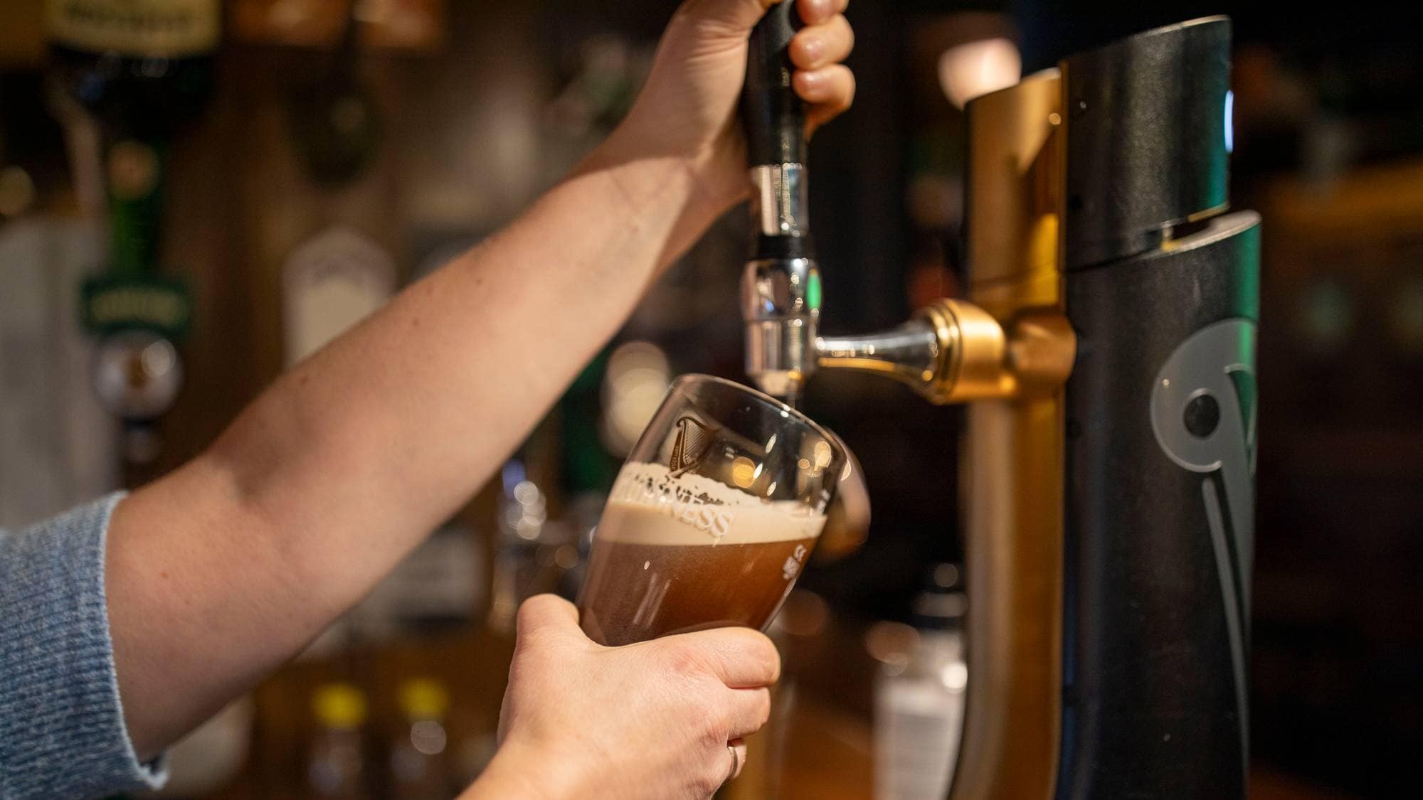 en person som heller en drink i et glass (Bildebeskrivelsen er laget av en KI-tjeneste)