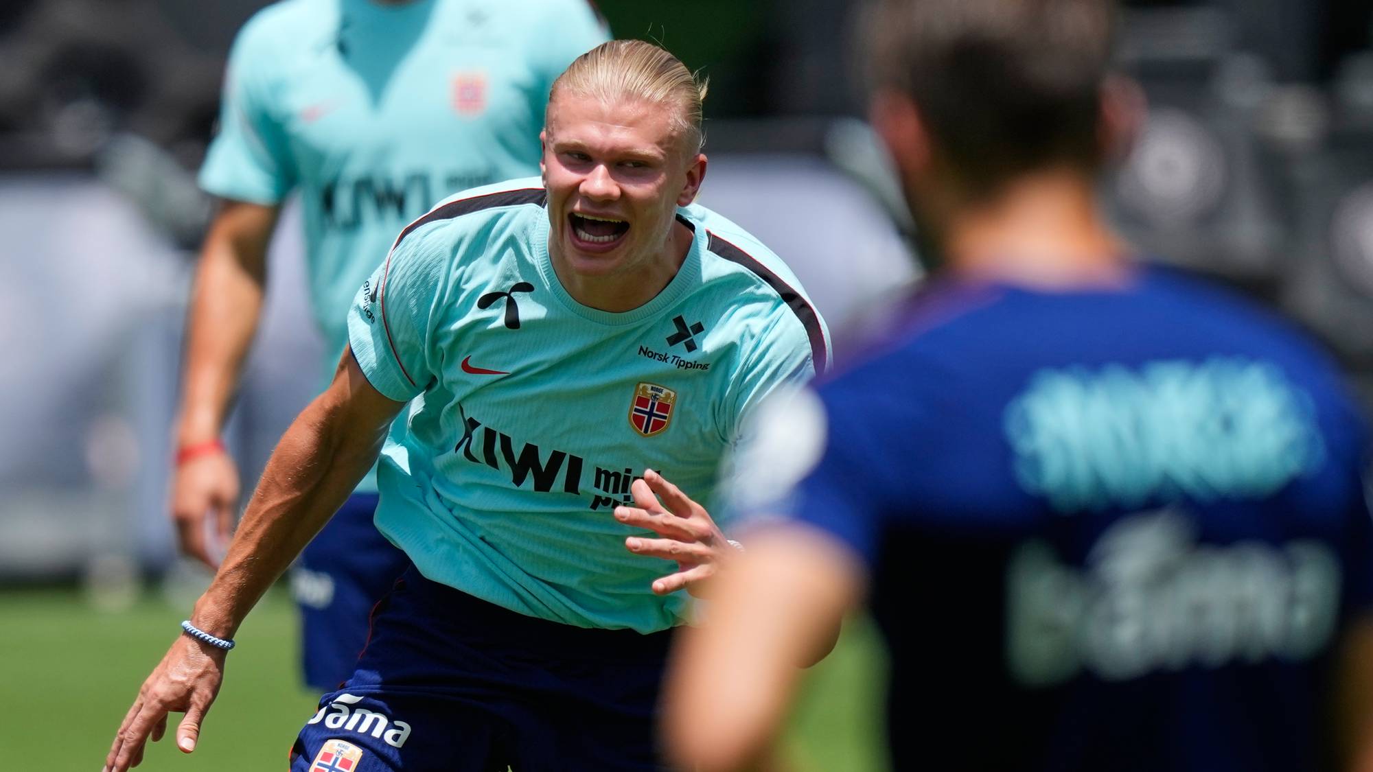 Erling Braut Haaland roper på treningsfeltet sammen med landslagsspillere i Norge-drakter. (Bildebeskrivelsen er laget av en KI-tjeneste)