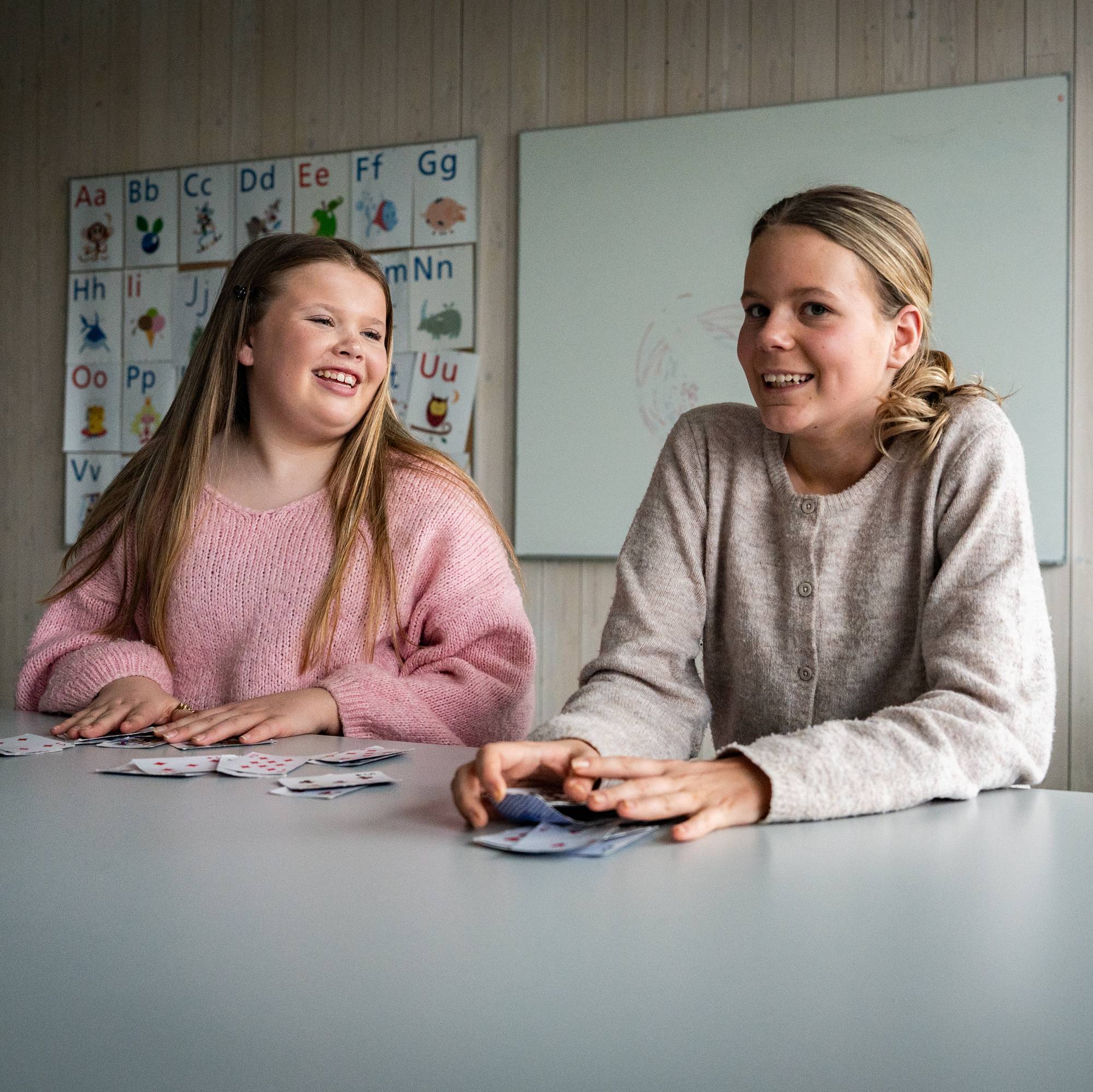 To jenter som sitter ved en pult på skolen.