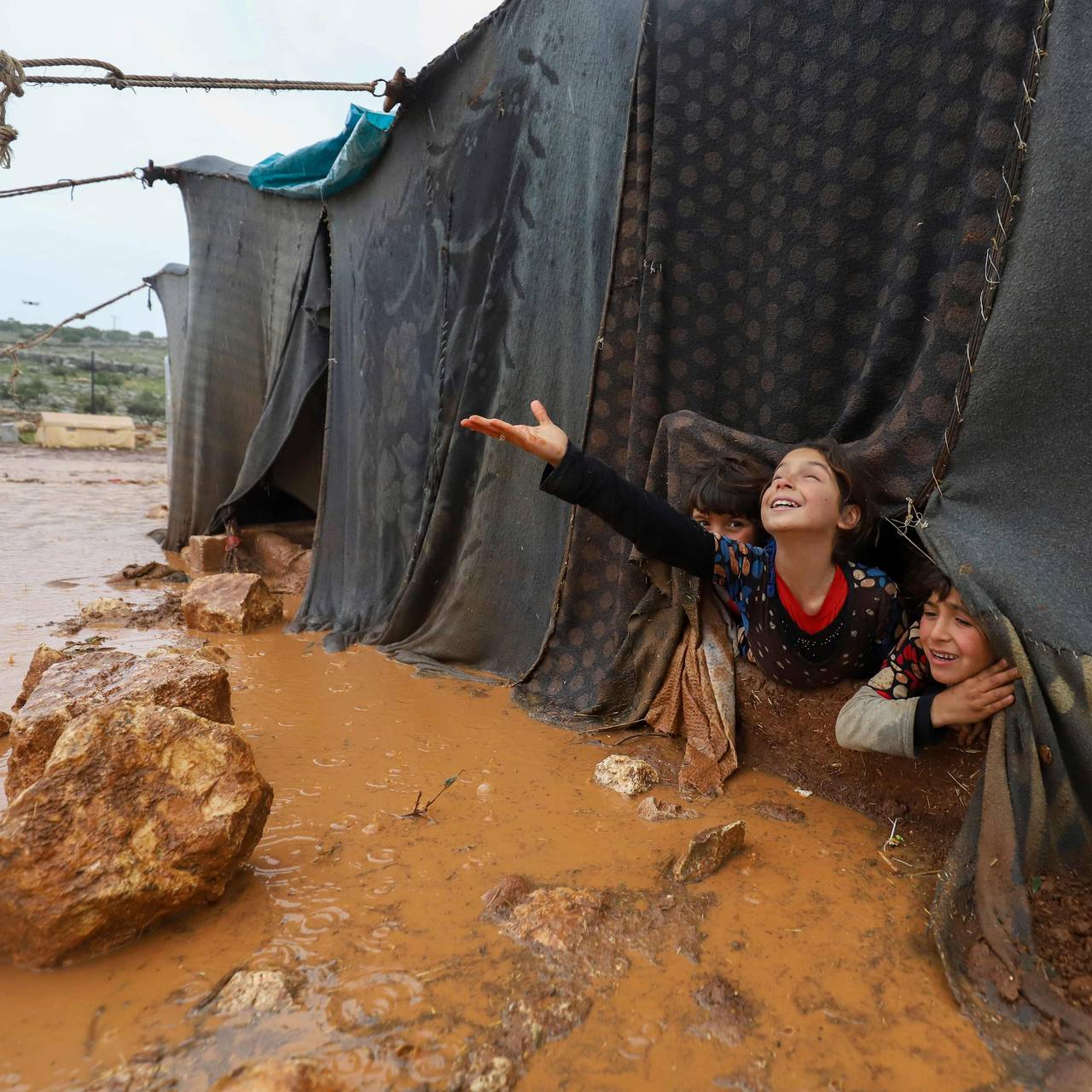 Barn leker etter kraftig regnvær har rammet en teltleir i Idlib-provinsen. 