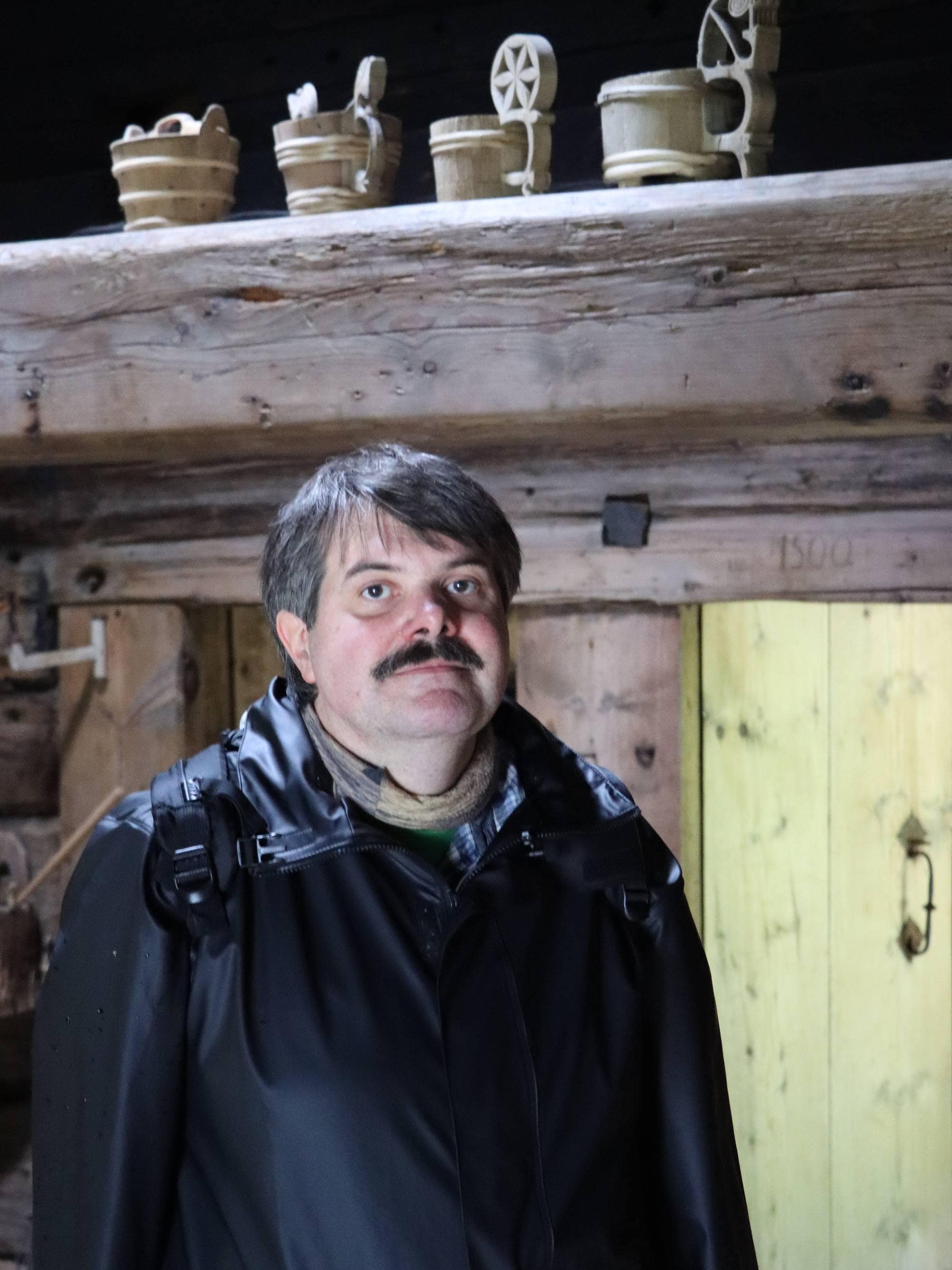 Mann som ser i kamera. Ovanfor er det gamle skålar.