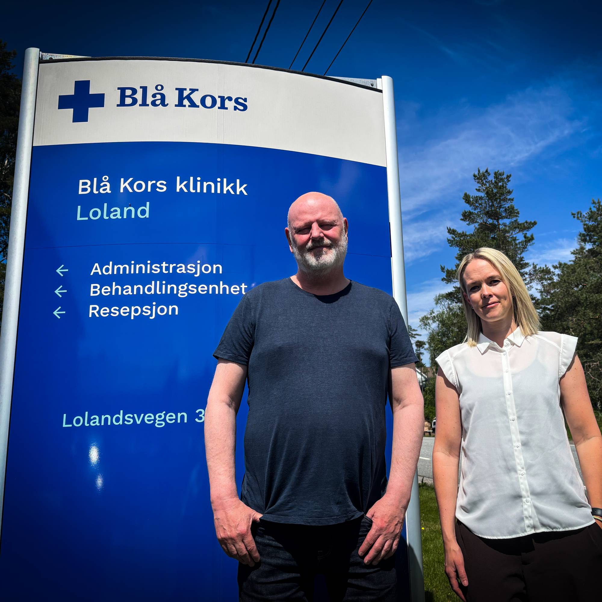 En mann og en kvinne står ved siden av et skilt. 