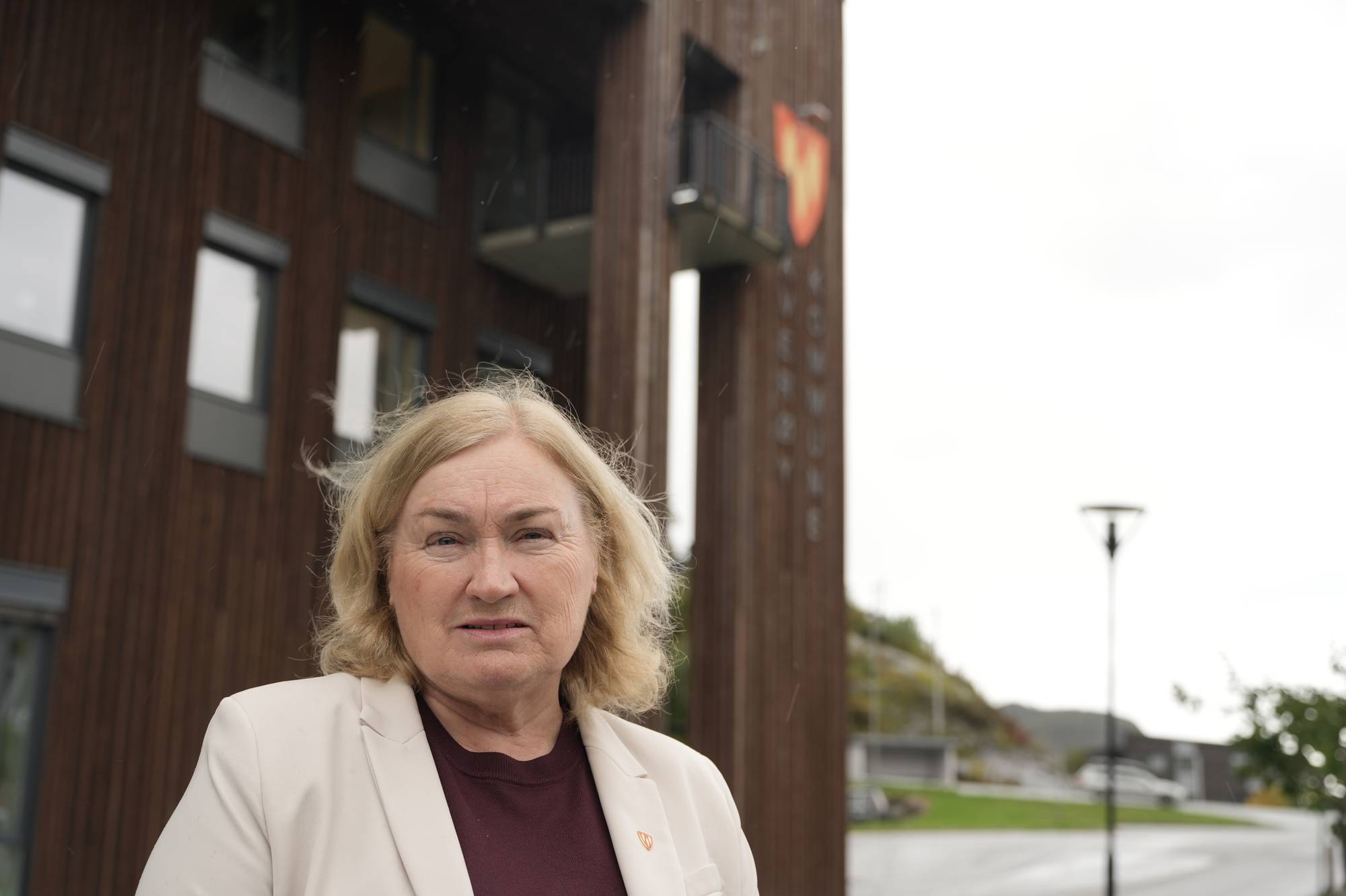 Kvinne foran Averøy kommunehus. (Bildebeskrivelsen er laget av en KI-tjeneste)