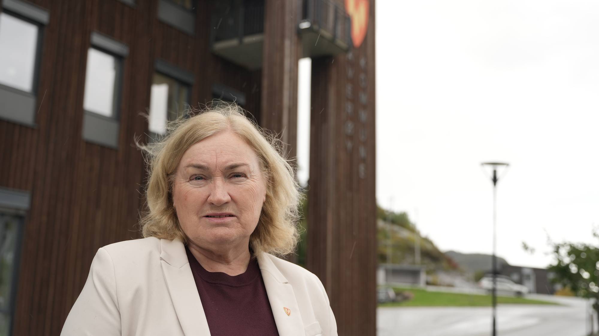 Kvinne foran Averøy kommunehus. (Bildebeskrivelsen er laget av en KI-tjeneste)