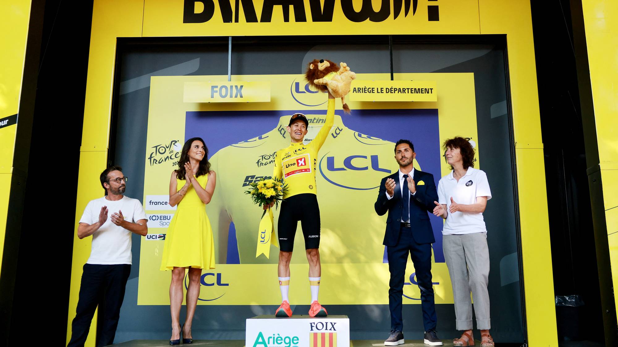 Syklist Jonas Vingegaard på pallen i gul ledertrøye under Tour de France i Foix. (Bildebeskrivelsen er laget av en KI-tjeneste)