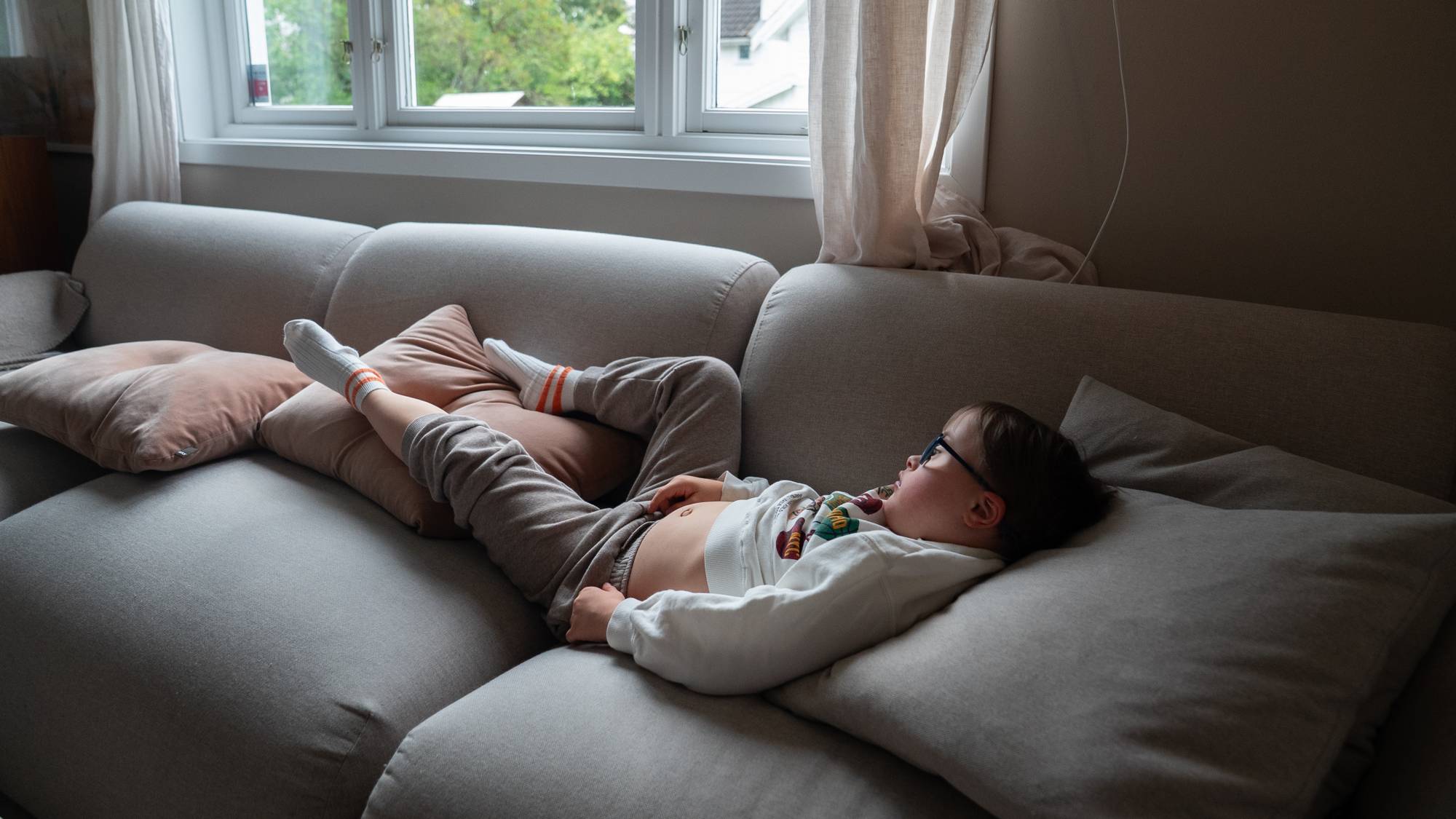 Gutt ligger på sofaen og ser opp mot taket. 