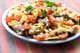 Matthew Mead / FR170582,NTB Nærbilde av nachos med smeltet ost, tomater, løk og paprika. Retten serveres på et rundt fat. (Bildebeskrivelsen er laget av en KI-tjeneste)