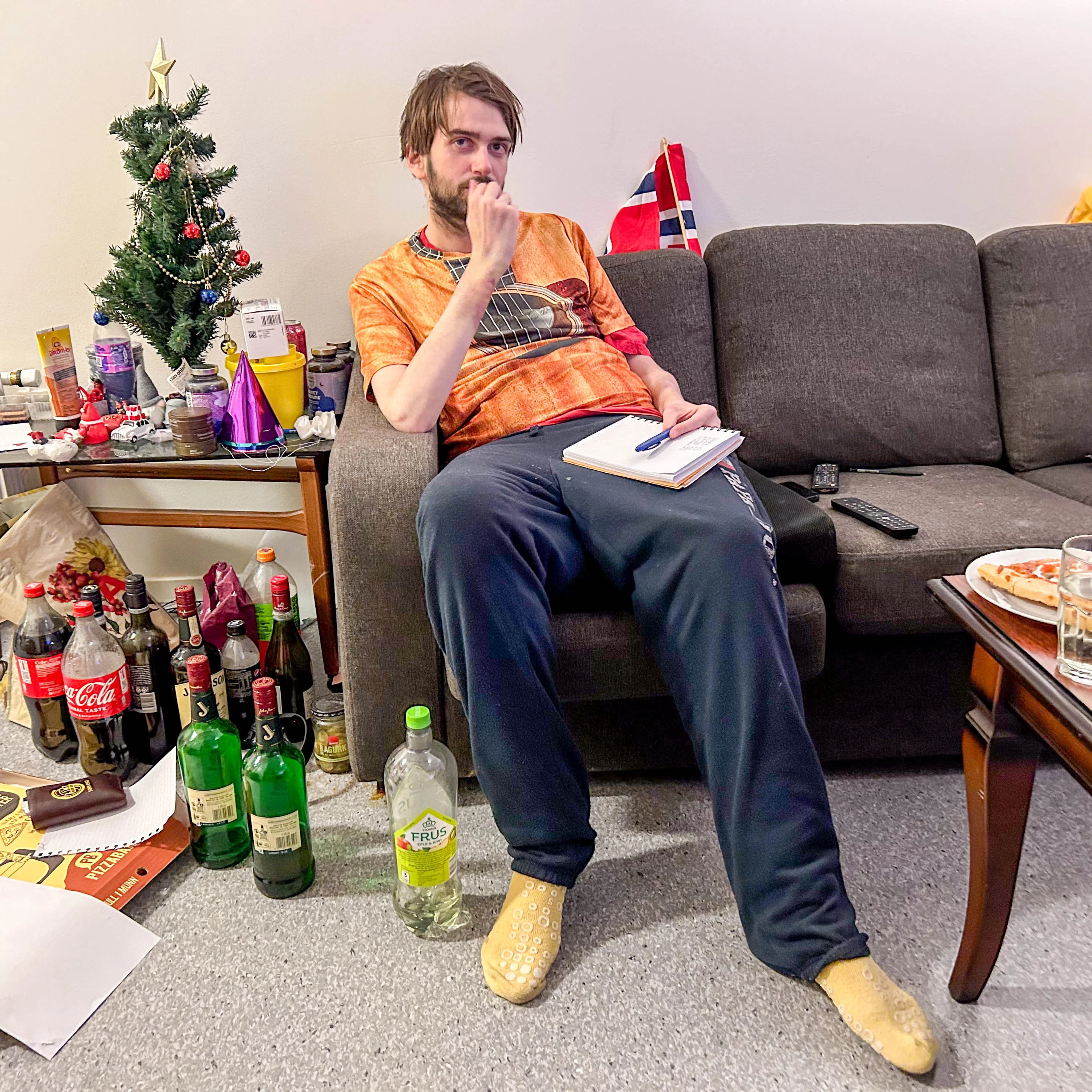 en person som sitter i en sofa og det er mye rot rundt