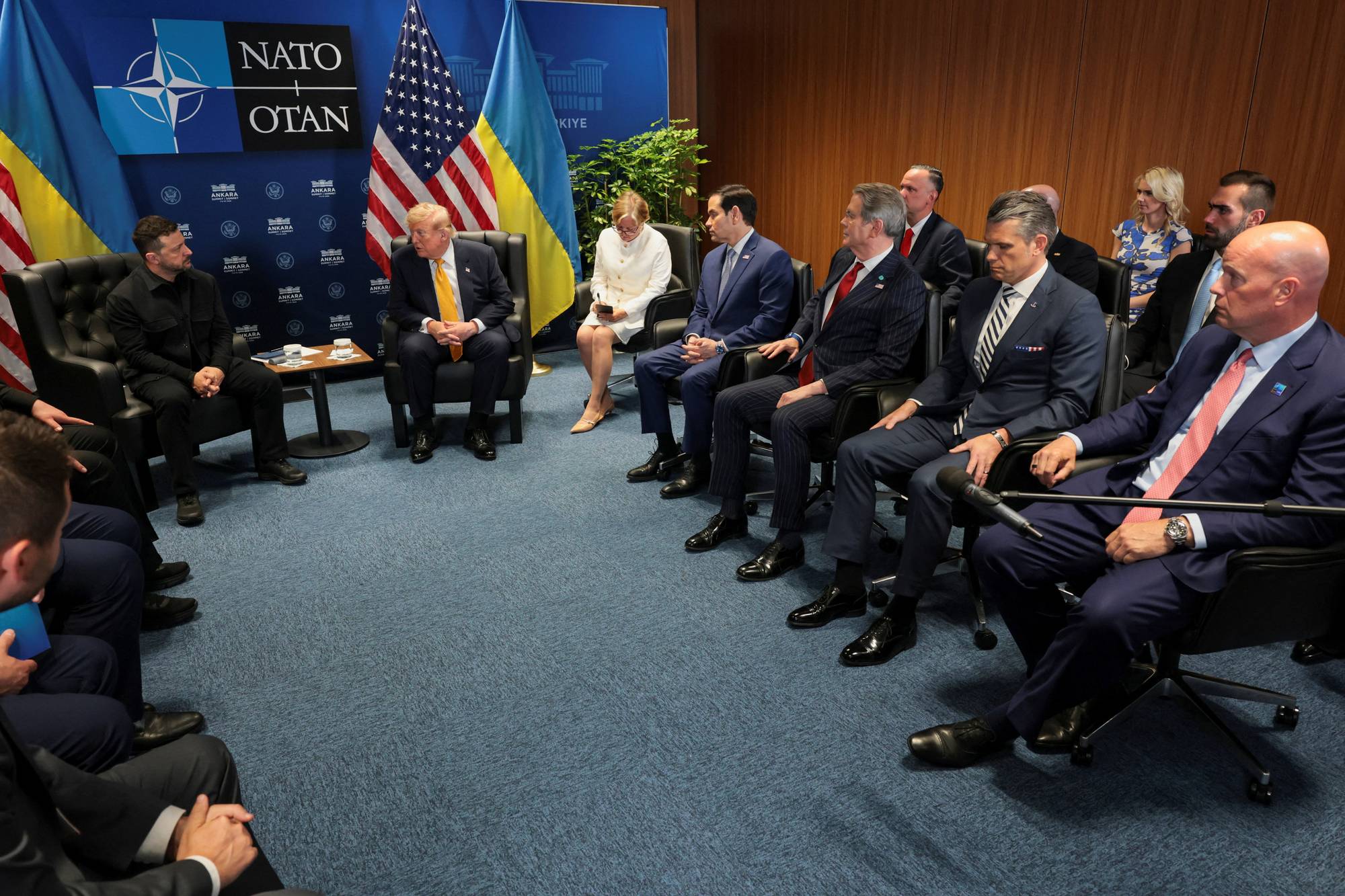 Volodymyr Zelenskyj møter Donald Trump og en delegasjon i et rom med NATO-flagg.
