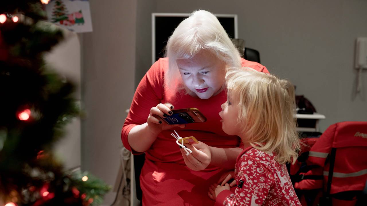 Mamma Ida-Martine Trollnes leser en historie fra julekalenderen "Pegga gris" til Nanna (2). Hun leser med lupe-app på mobilen.