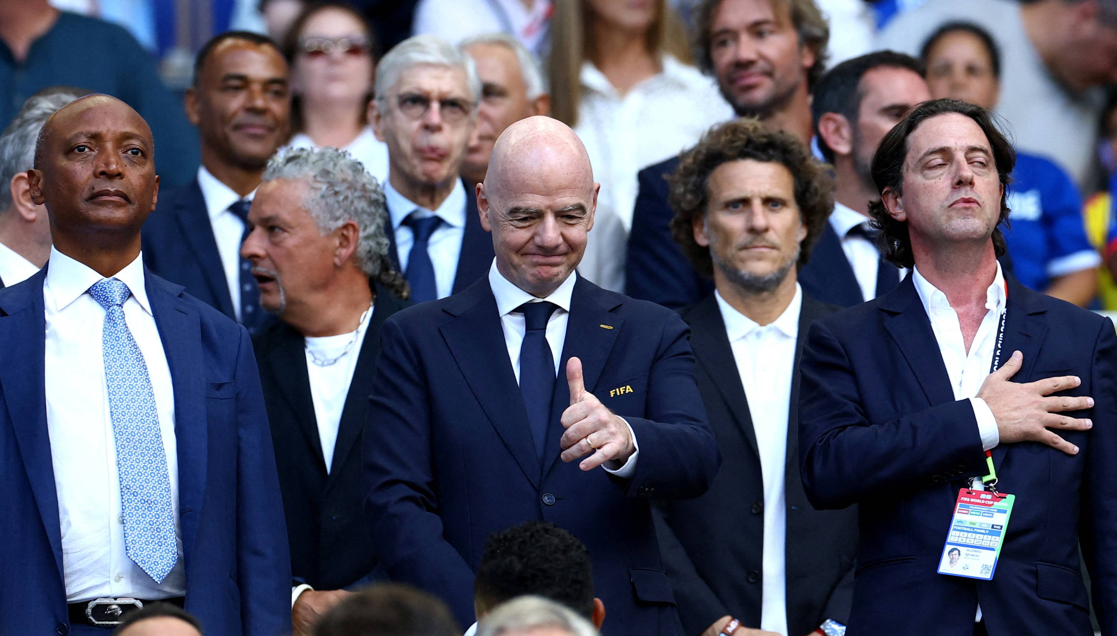 FIFA-president Gianni Infantino viser tommel opp blant andre personar på tribunen. (Bildebeskrivelsen er laget av ein KI-teneste)