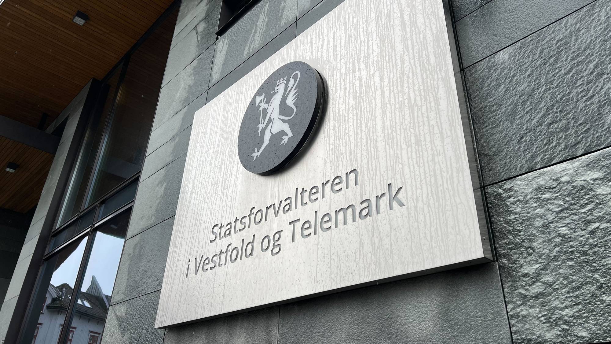 Bildet viser et skilt der det står Statsforvalteren i Vestfold og Telemark. Bak skimtes en grå vegg. 