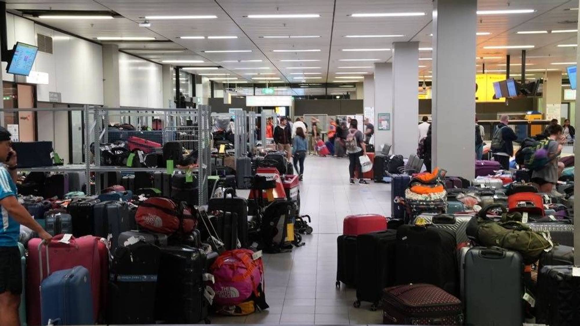 Hauger med kofferter og bager ligger strødd langs en korridor ved Schiphol lufthavn i Amsterdam.