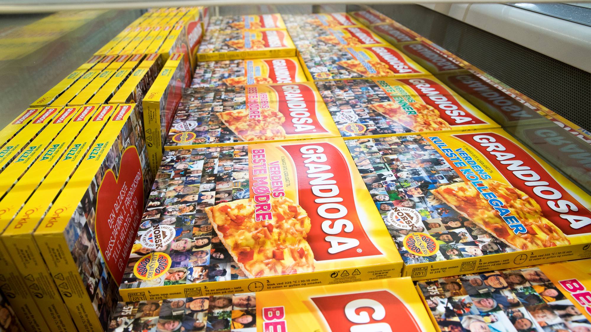 Flere esker med Grandiosa frossenpizza står stablet i en frysedisk i en dagligvarebutikk.