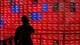 PHILIP FONG / AFP,NTB En person i silhuett ser på en stor skjerm med aksjekurser. Skjermen viser aksjekurser for flere selskaper, med røde tall som indikerer fallende kurser. En vannmerkelignende logo er plassert midt på skjermen. (Bildebeskrivelsen er laget av en KI-tjeneste)