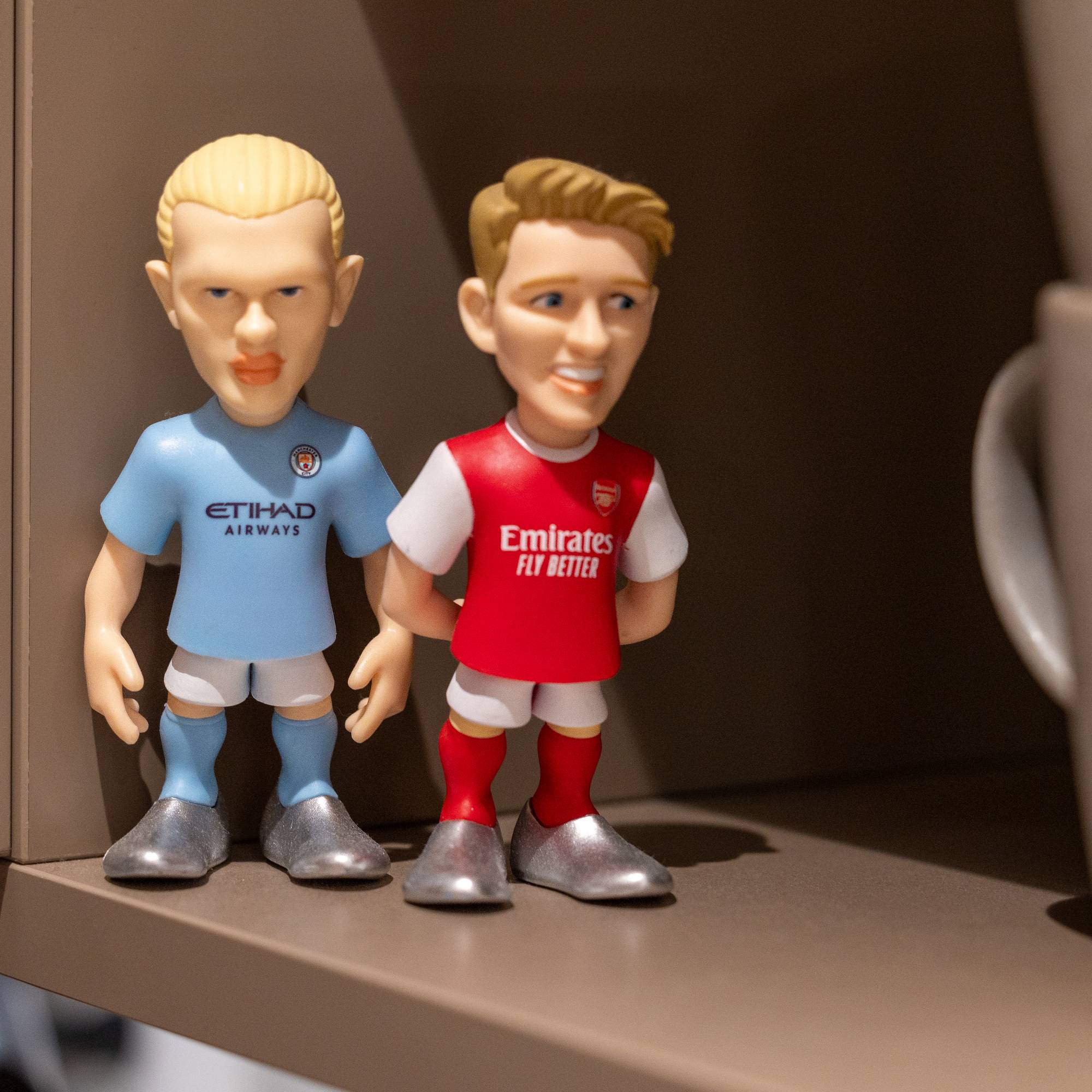 Små dokker av Erling Braut Haaland og Martin Ødegaard i ei kjøkkenhylle.