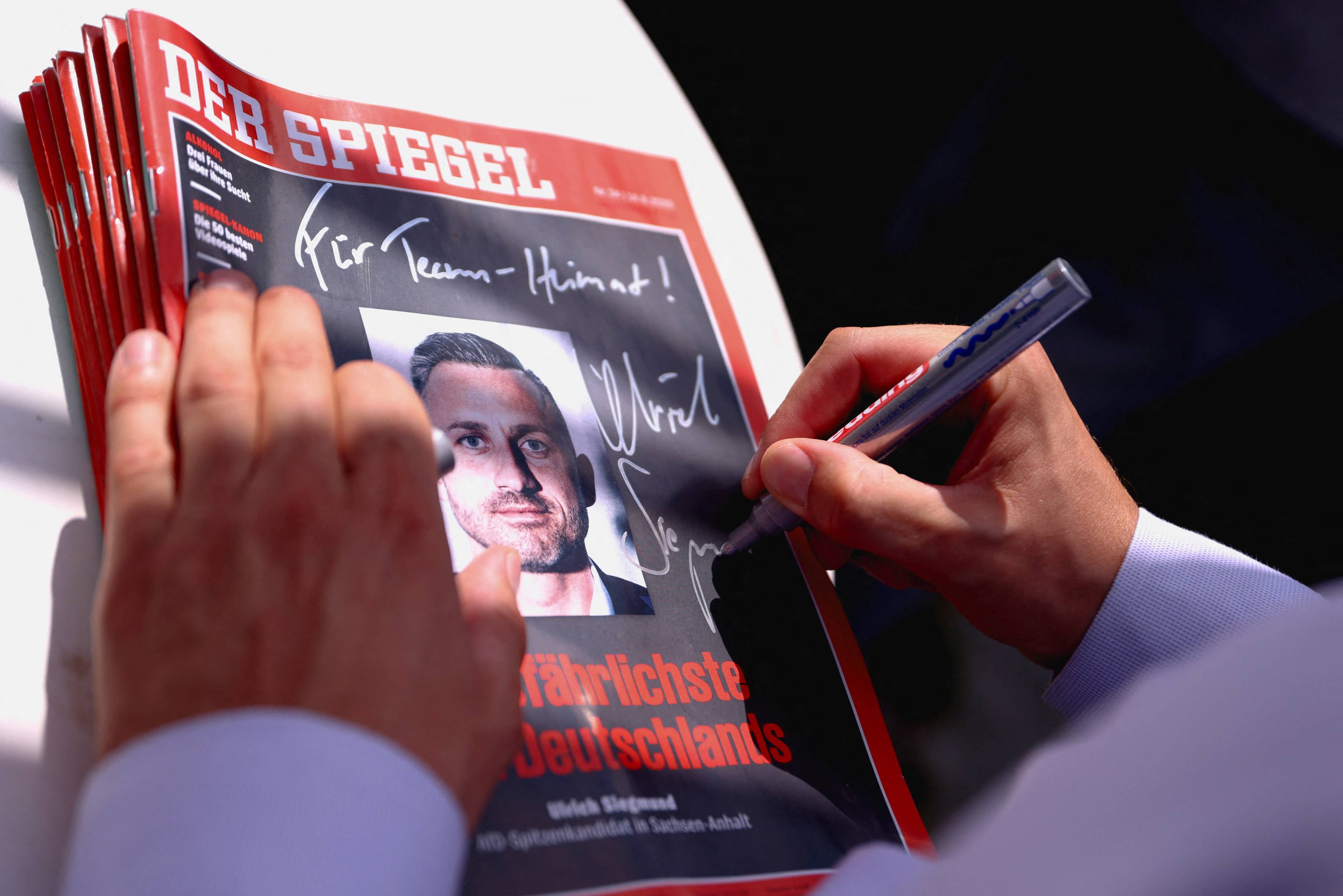 en hånd signerer Der Spiegel-forside som avbilder Ulrich Siegmund