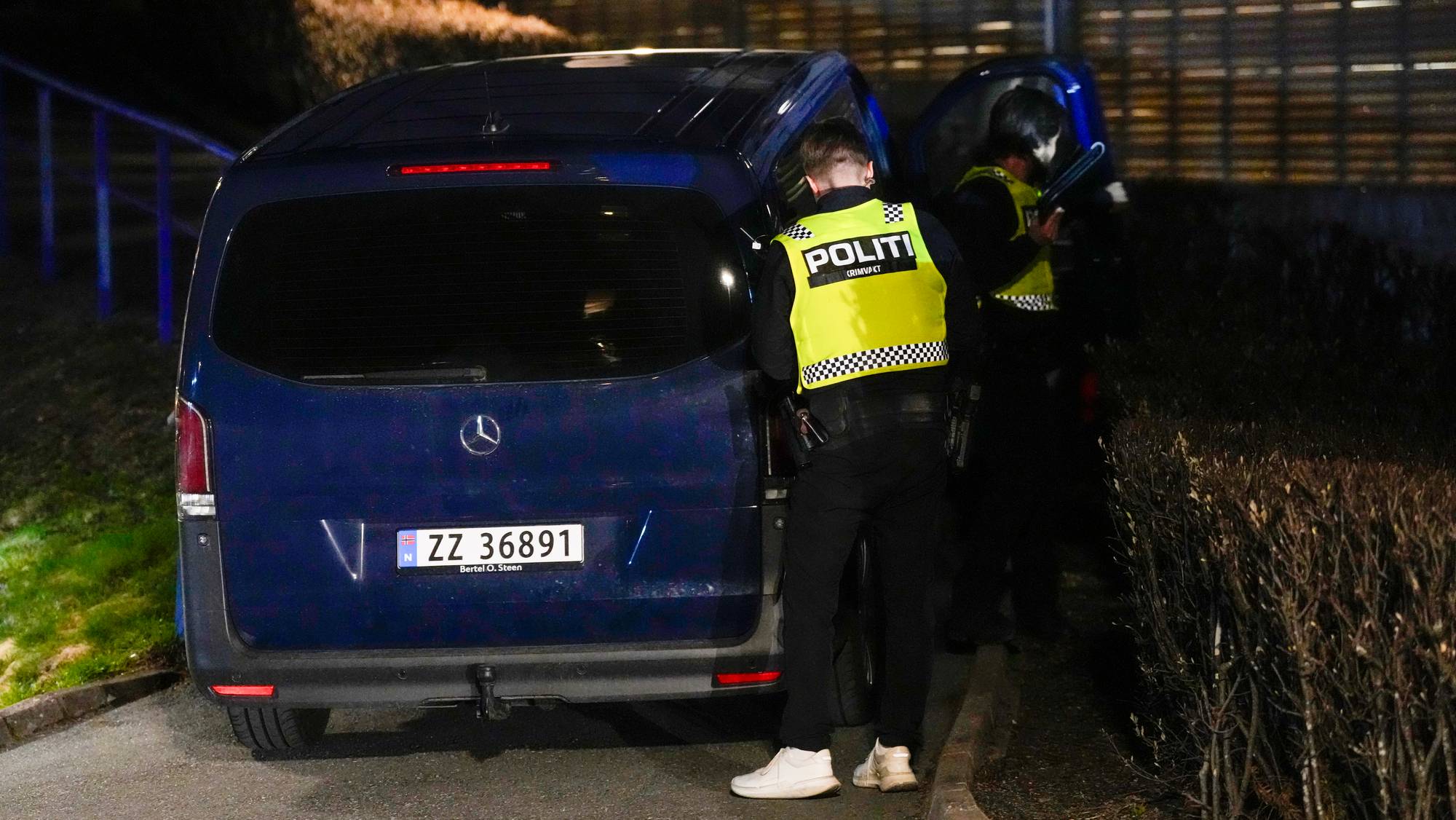To politibetjenter i gule vester står ved siden av en mørkeblå varebil. Bildet er tatt om natten. Varebilen har et norsk registreringsnummer ZZ 36891. (Bildebeskrivelsen er laget av en KI-tjeneste)