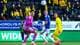 Mats Torbergsen / NTB Fotballspillere i aksjon under en kamp. En keeper i lilla drakt og to utespillere. Tilskuere sitter på tribunen i bakgrunnen. (Bildebeskrivelsen er laget av en KI-tjeneste)