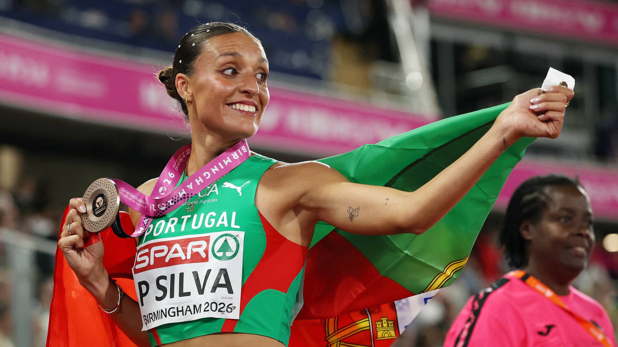 Friidrettsutøver P. Silva feirer med portugisisk flagg og medalje etter mesterskap i Birmingham. (Bildebeskrivelsen er laget av en KI-tjeneste)
