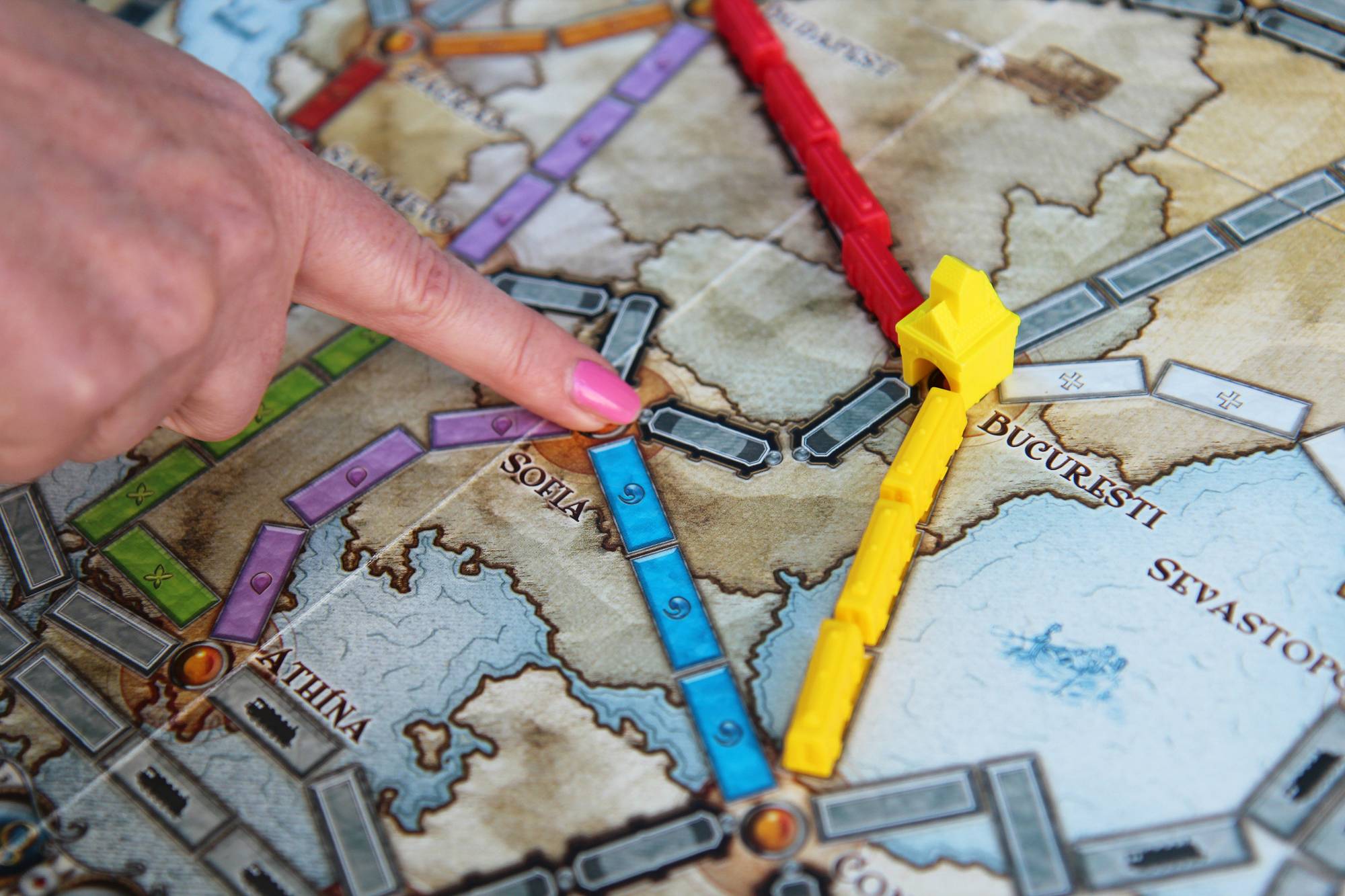 Nærbilde av brettspillet Ticket to Ride. En kvinnehånd peker med pekefingeren mot Sofia.