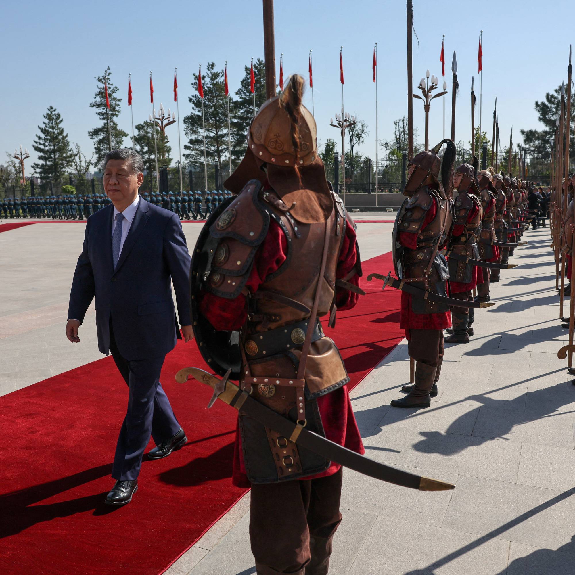 Xi Jinping og Sadyr Japarov går på en rød løper forbi en æresvakt i historiske uniformer. (Bildebeskrivelsen er laget av en KI-tjeneste)
