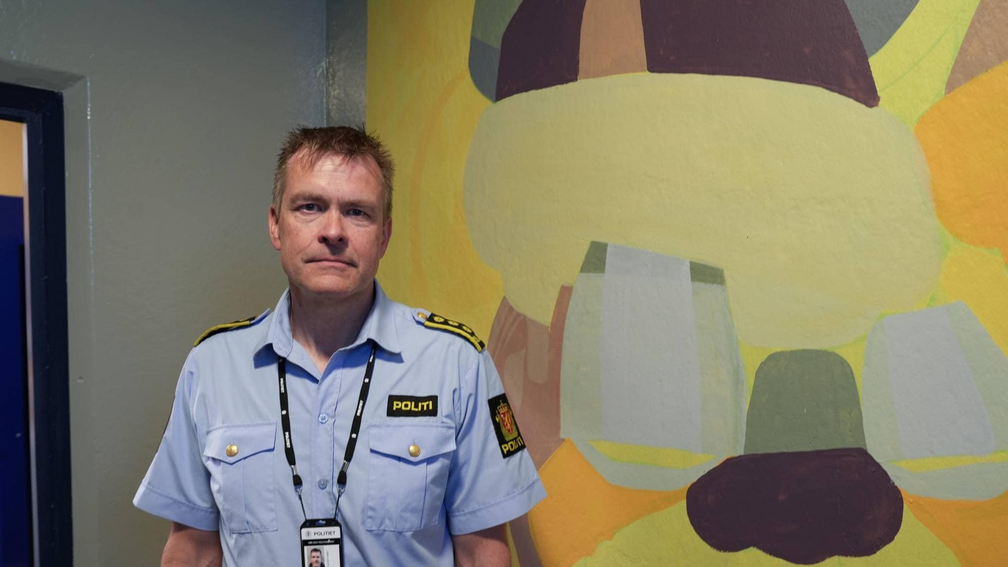 Politimann Eirik Jansen Bakkedal foran et veggmaleri på ei glattcelle på Politihuset i Stavanger. 