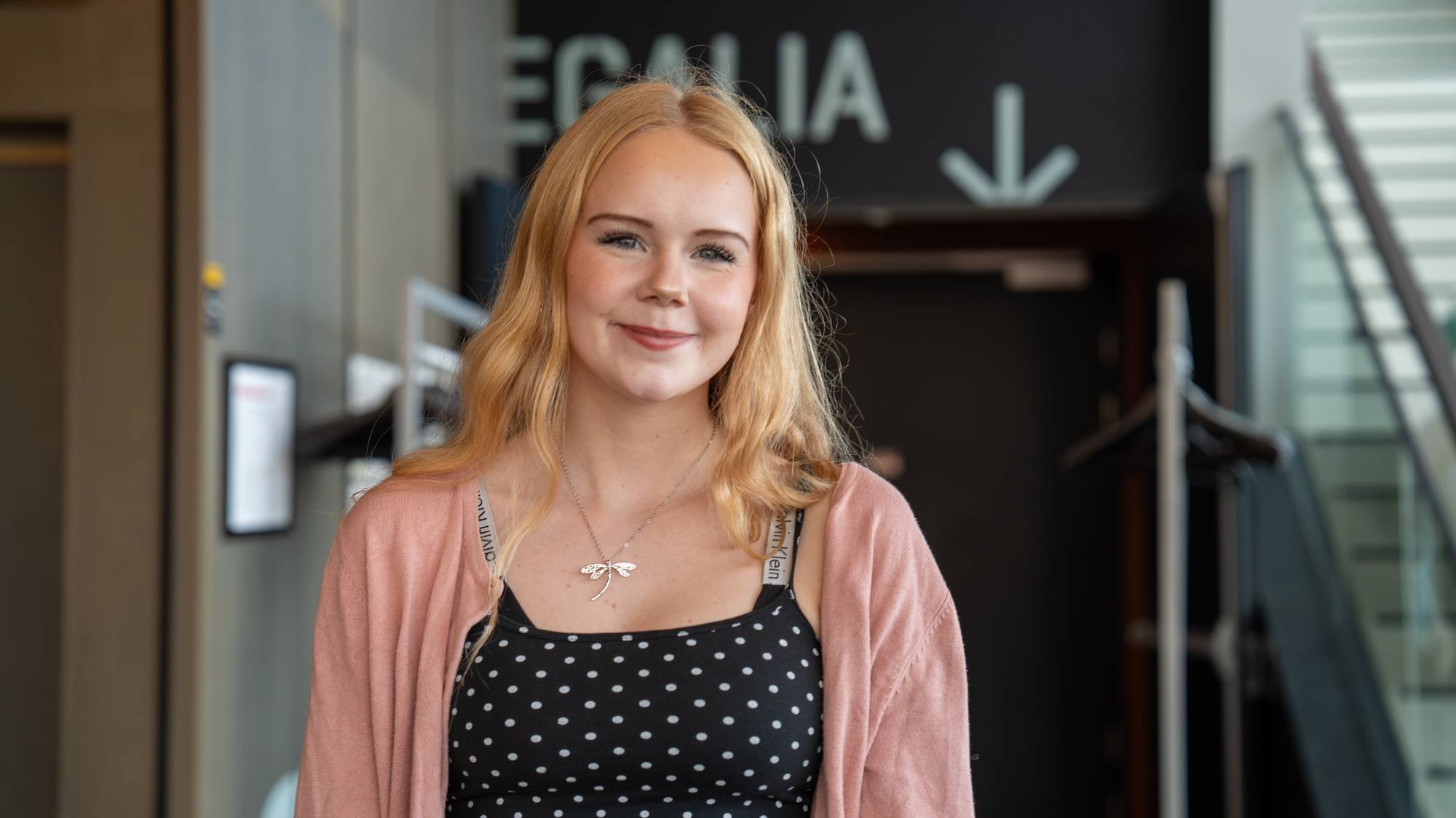 Portrett av en ung kvinne med langt, lyst hår som smiler inn i kameraet. (Bildebeskrivelsen er laget av en KI-tjeneste)
