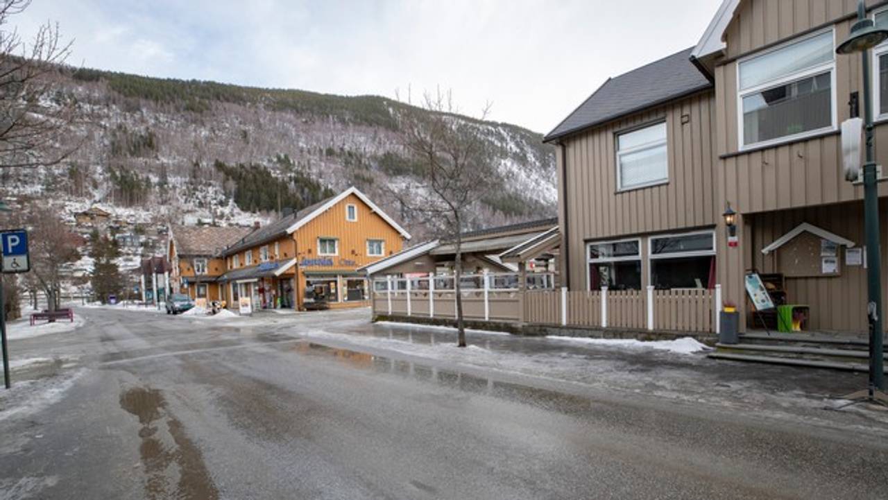 Gatebilde fra Otta, et par hus ligger langs en regnvåt vei.