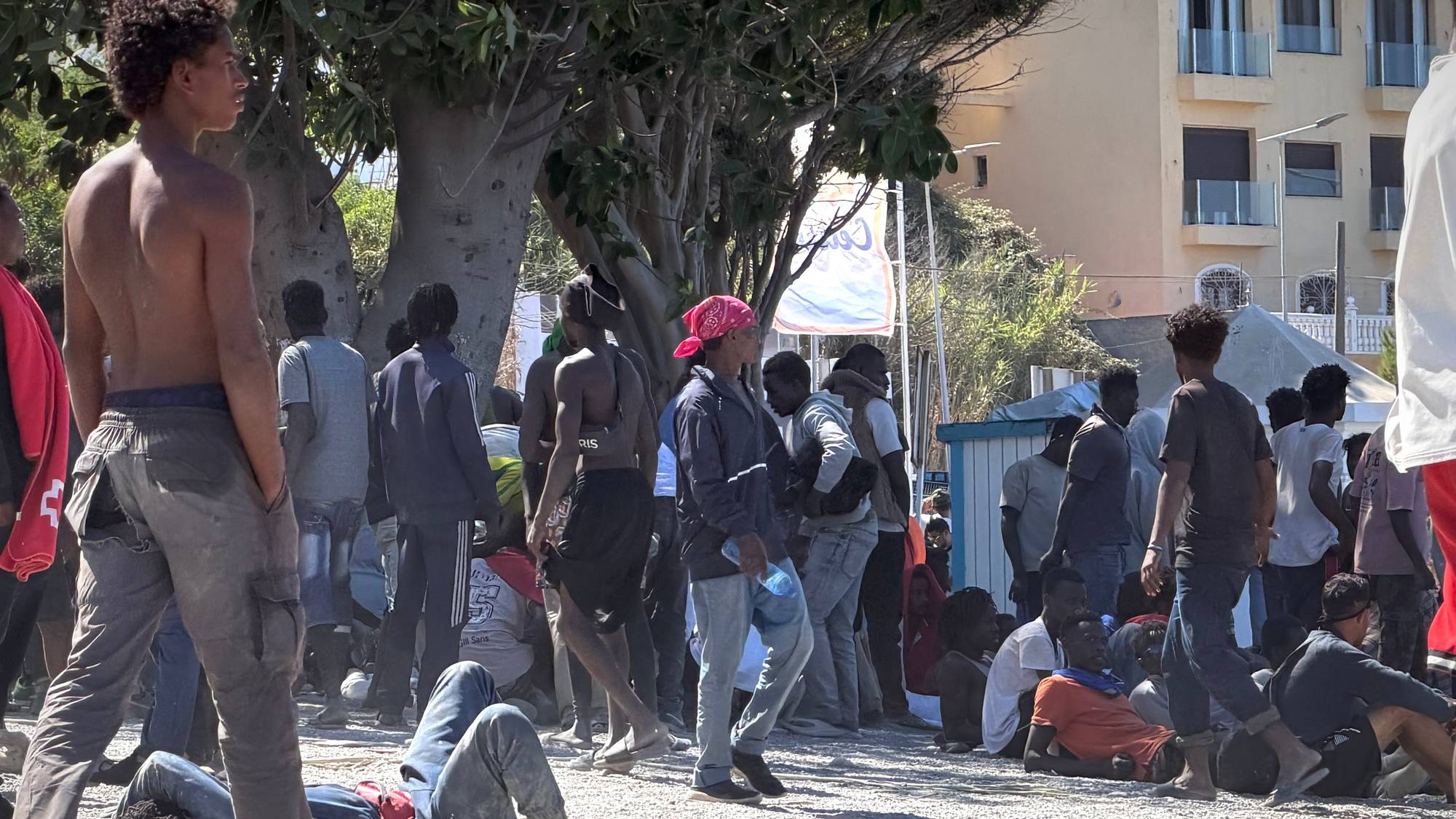 Ei gruppe unge menn med afrikansk utsjånad oppsøker skuggen på ei strand i Ceuta.