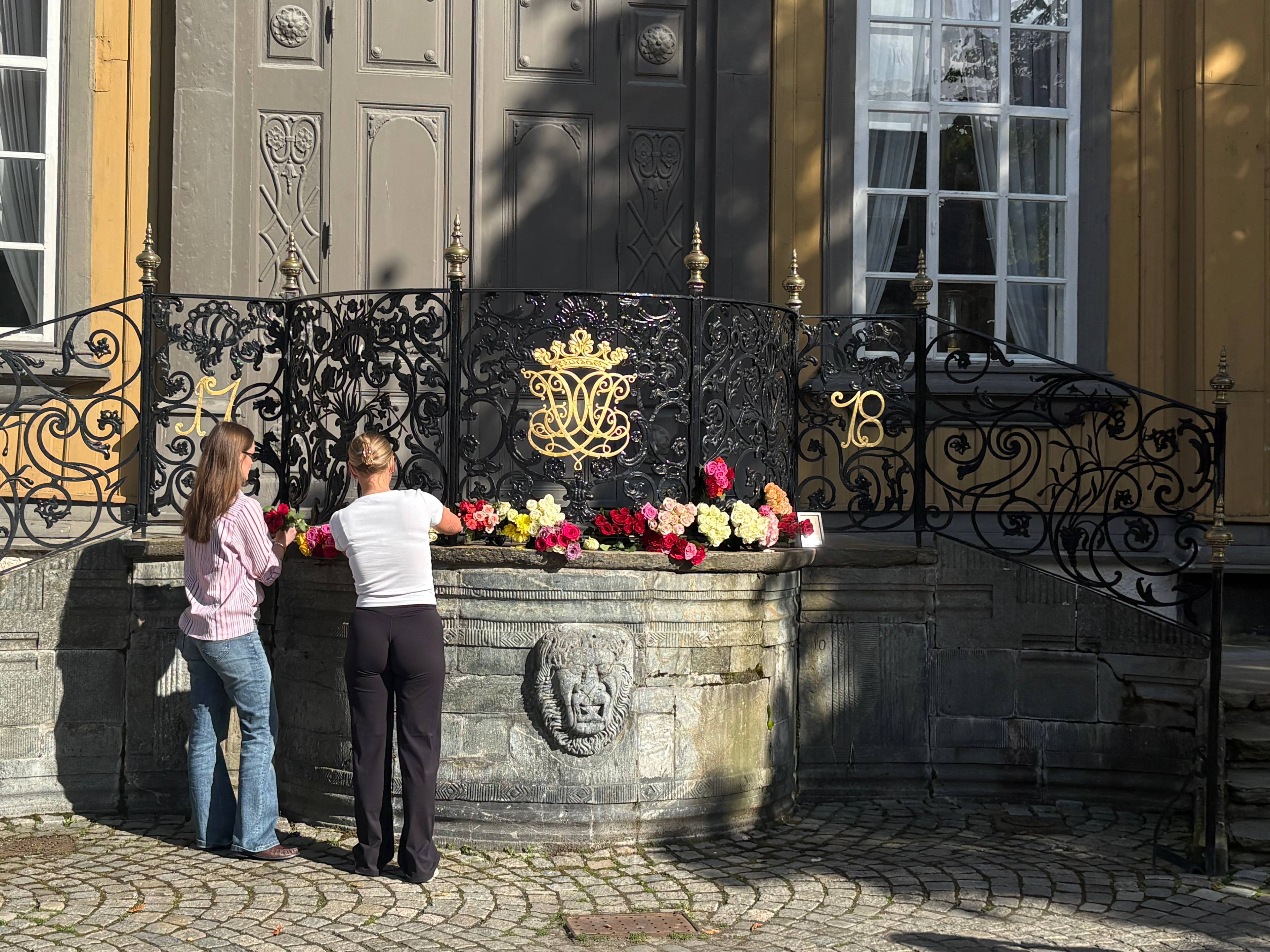 To damer legger ned blomster utenfor Stiftsgården i Trondheim.