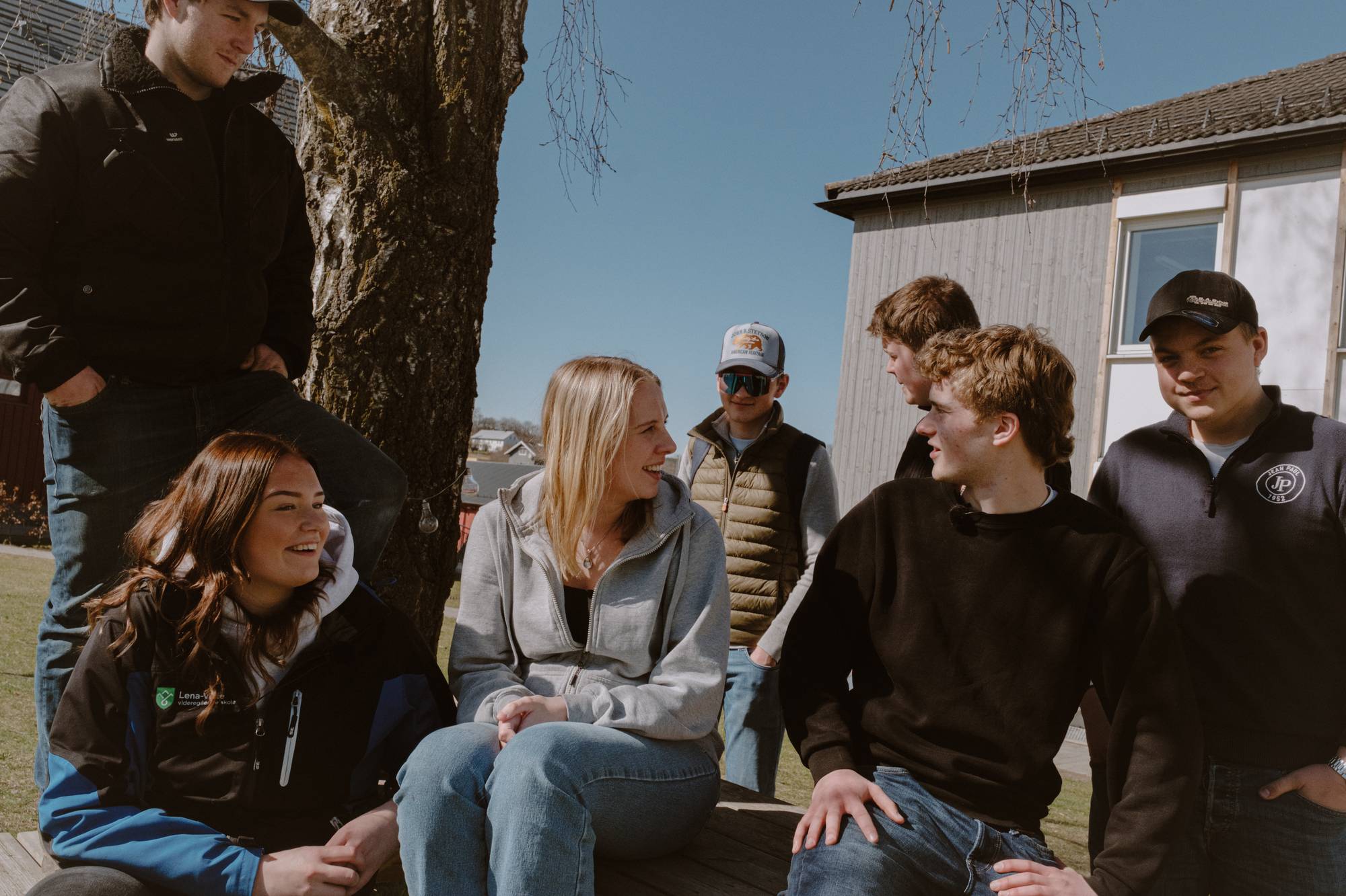En gruppe elever sitter utendørs rundt en benk