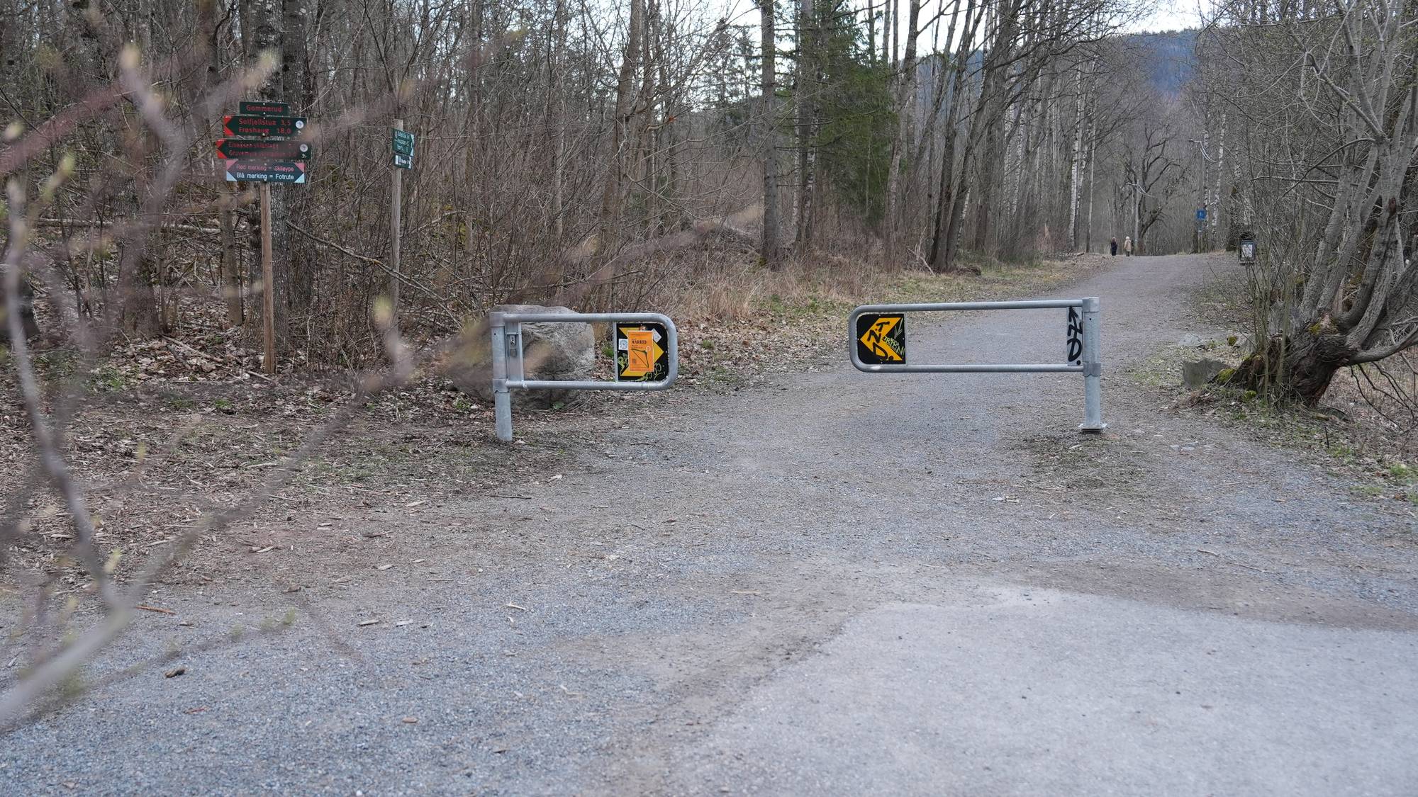 To stier, en asfaltert og en grusbelagt, møtes i en skogkledd bakke. Stiene er sperret av med metallgrinder med skilt. En skilting viser veien til Goldeiken, Breiskogg og Vargenåsen. (Bildebeskrivelsen er laget av en KI-tjeneste)