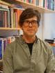 Jonas Ørbeck Sire / NRK En mann med briller ser i kamera, bak ham er det ei stor bokhylle med masse bøker.