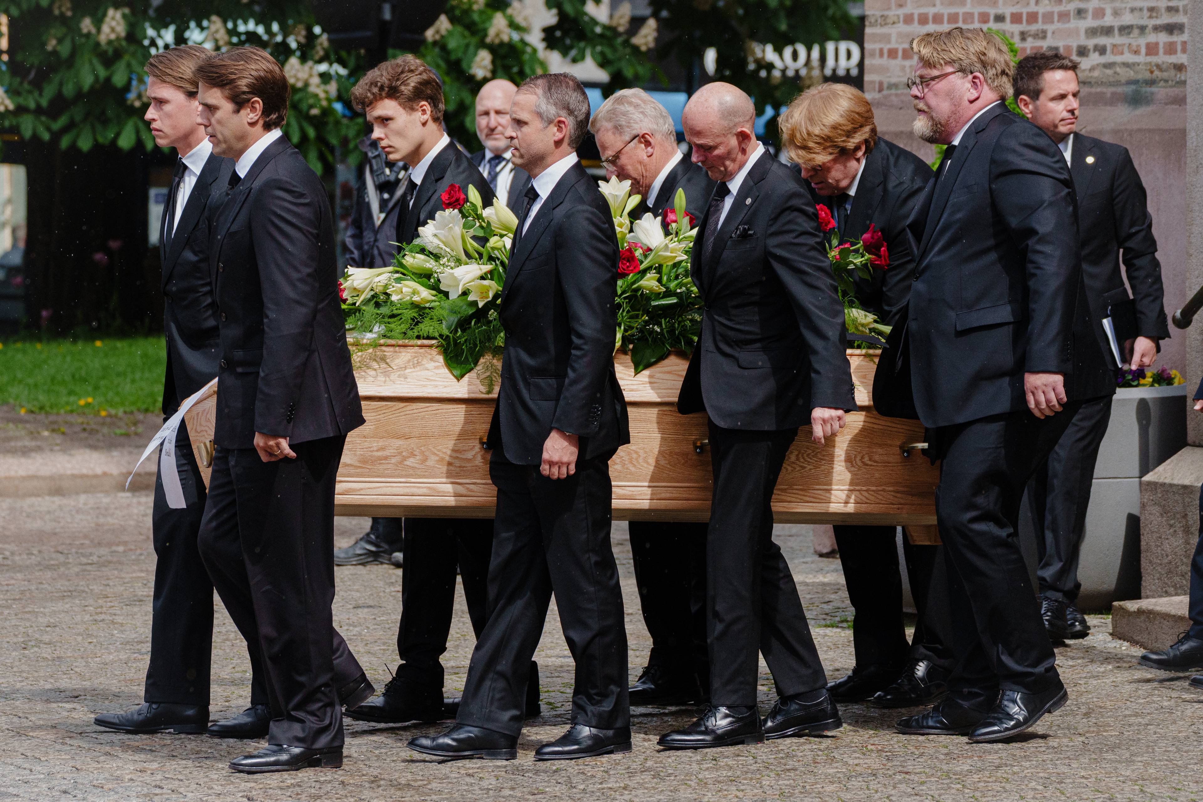En gruppe menn bærer en kiste utenfor en kirke