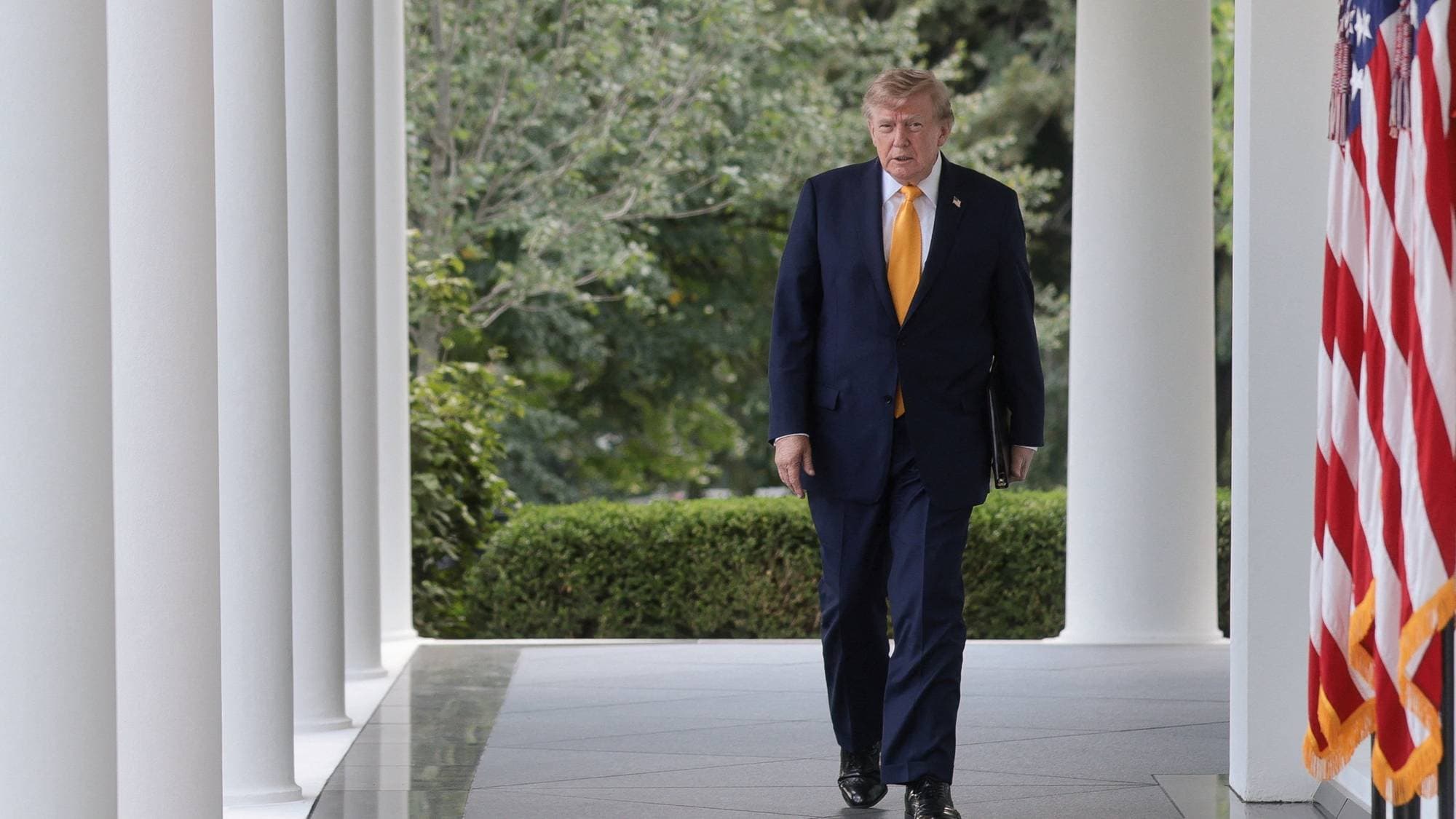 Donald Trump går utenfor Det hvite hus med amerikanske flagg i bakgrunnen. (Bildebeskrivelsen er laget av en KI-tjeneste)