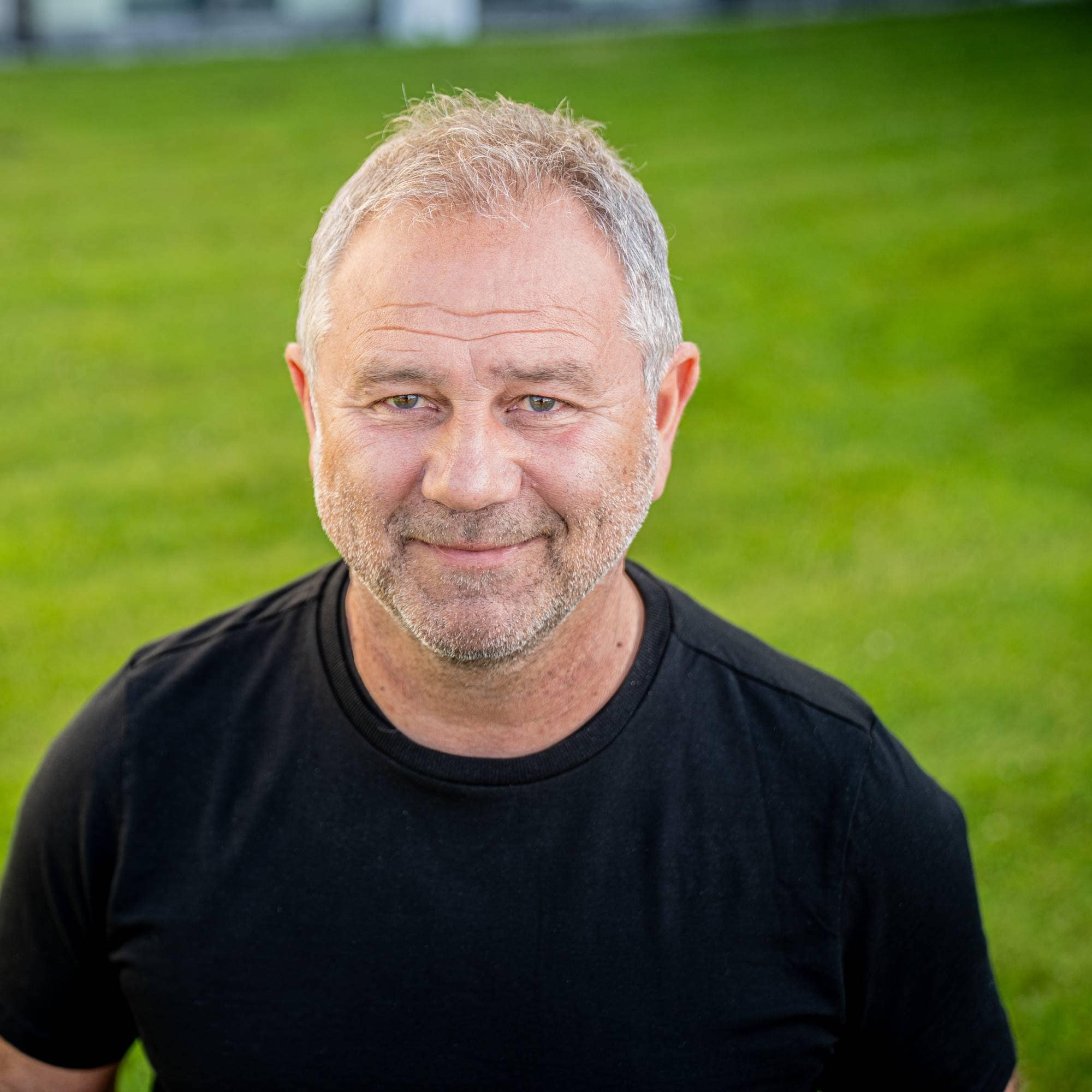Fotballekspert Bengt Eriksen står på grønt gress og smiler. 