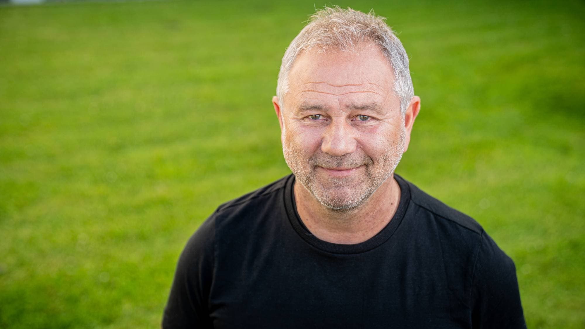 Fotballekspert Bengt Eriksen står på grønt gress og smiler. 