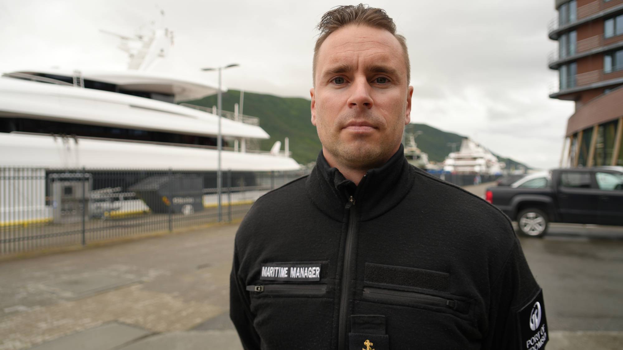 Maritime Manager for Port of Tromsø ved havnen med en stor båt i bakgrunnen. (Bildebeskrivelsen er laget av en KI-tjeneste)