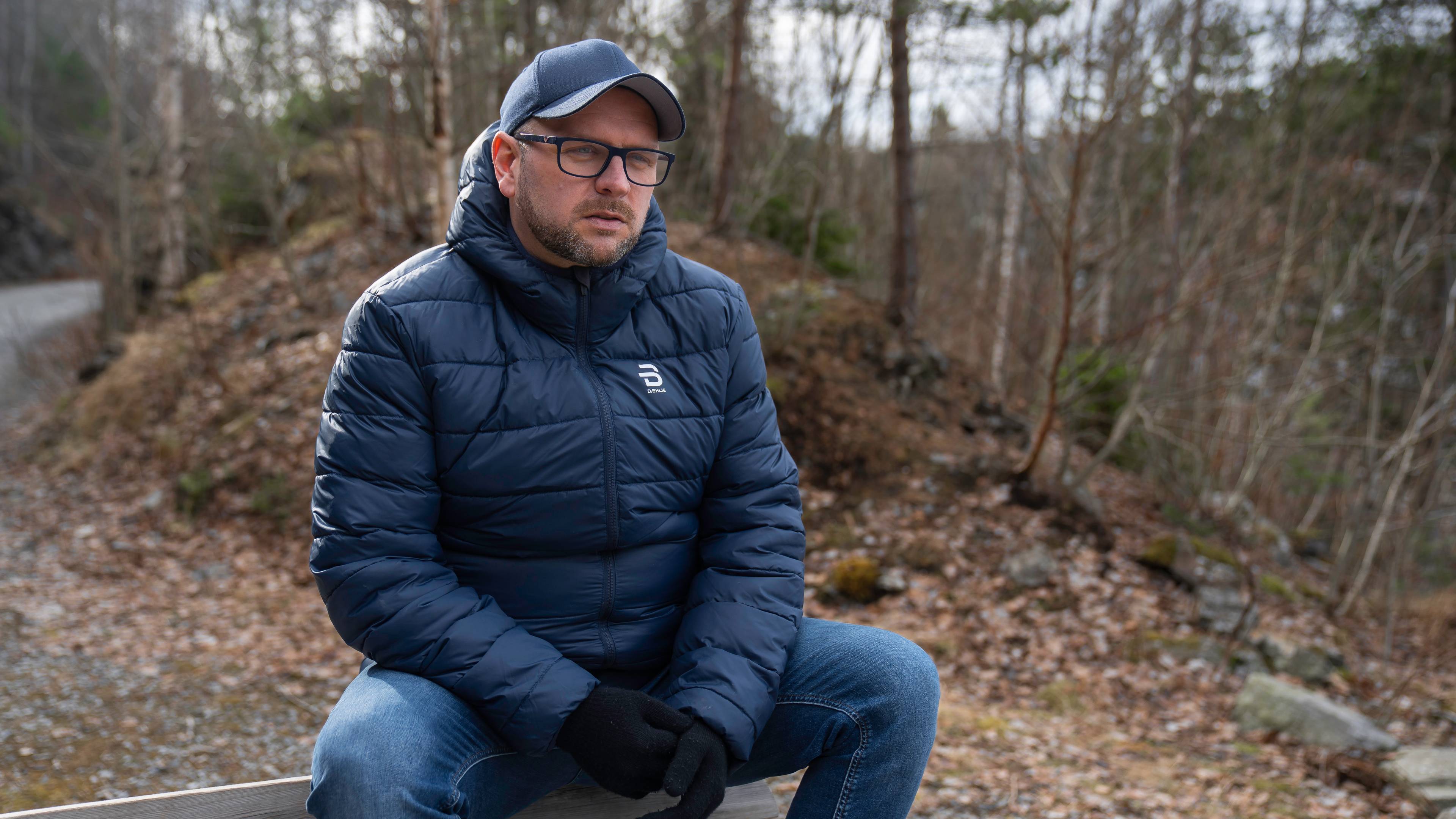 Mann sitter på benk med hendene i fanget
