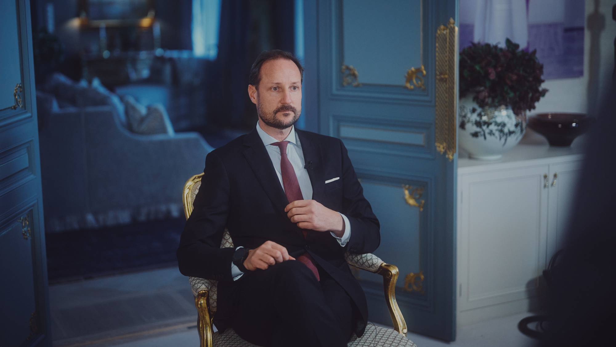 Kronprins Haakon sitter i en stol på Skaugum og gjør seg klar til å bli intervjuet, mens han retter litt på slipset