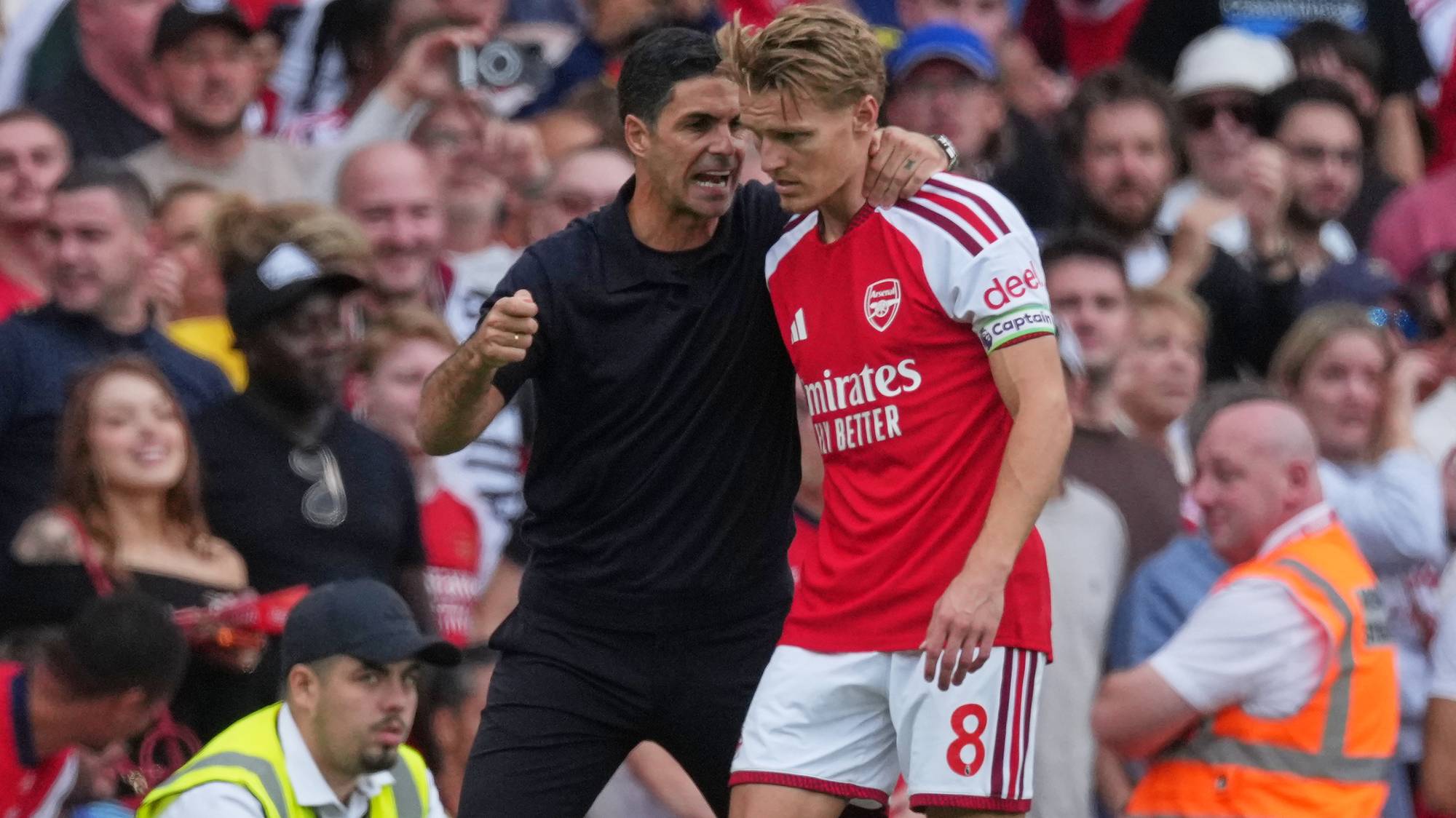 Arsenal-trener Mikel Arteta gir instrukser til spilleren Martin Ødegaard på en fotballbane. (Bildebeskrivelsen er laget av en KI-tjeneste)