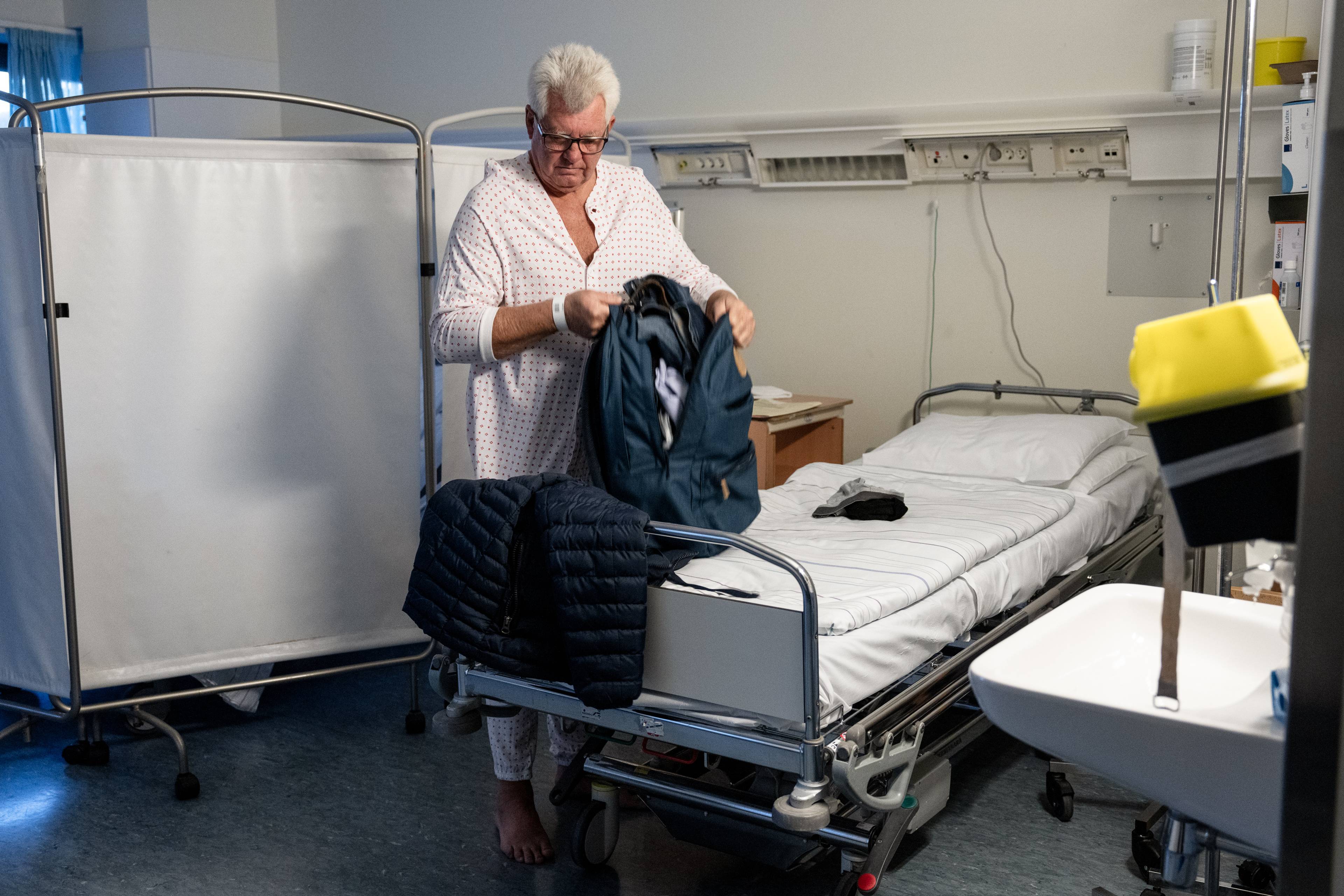 Erik gjør seg klar for operasjon ved sengen på sykehuset. Han tar av seg jakken og tar på sykehusskjorten.