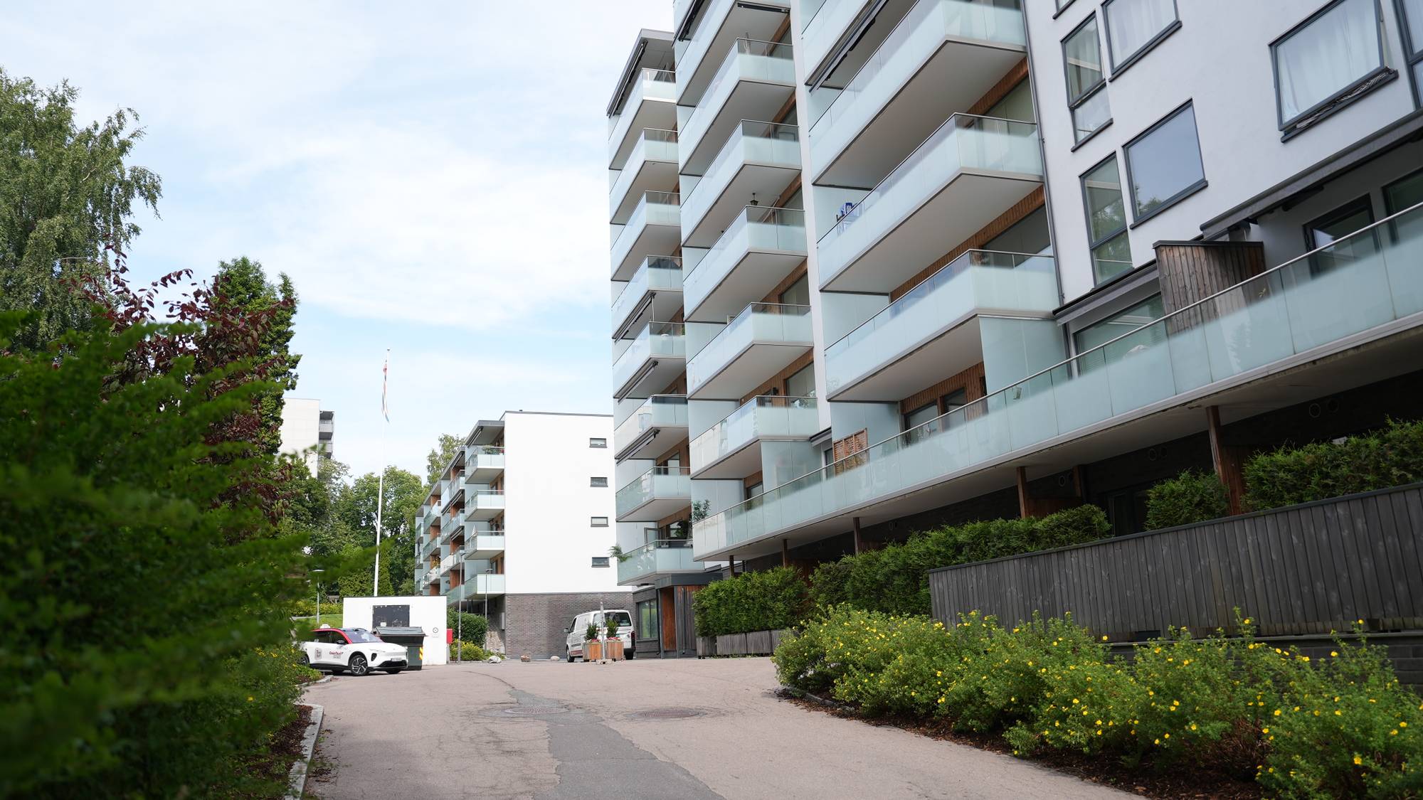 Moderne hvite boligblokker med balkonger i et boligområde.