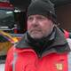 Tomas Berger / NRK En person i en rød arbeidsjakke med refleksstriper står foran en snøplog og en lastebil. Bakgrunnen viser et verksted med snø på bakken. Personen ser ut til å gi et intervju eller en uttalelse. Vanskelige værforhold kan være en del av konteksten. (Bildebeskrivelsen er laget av en KI-tjeneste)