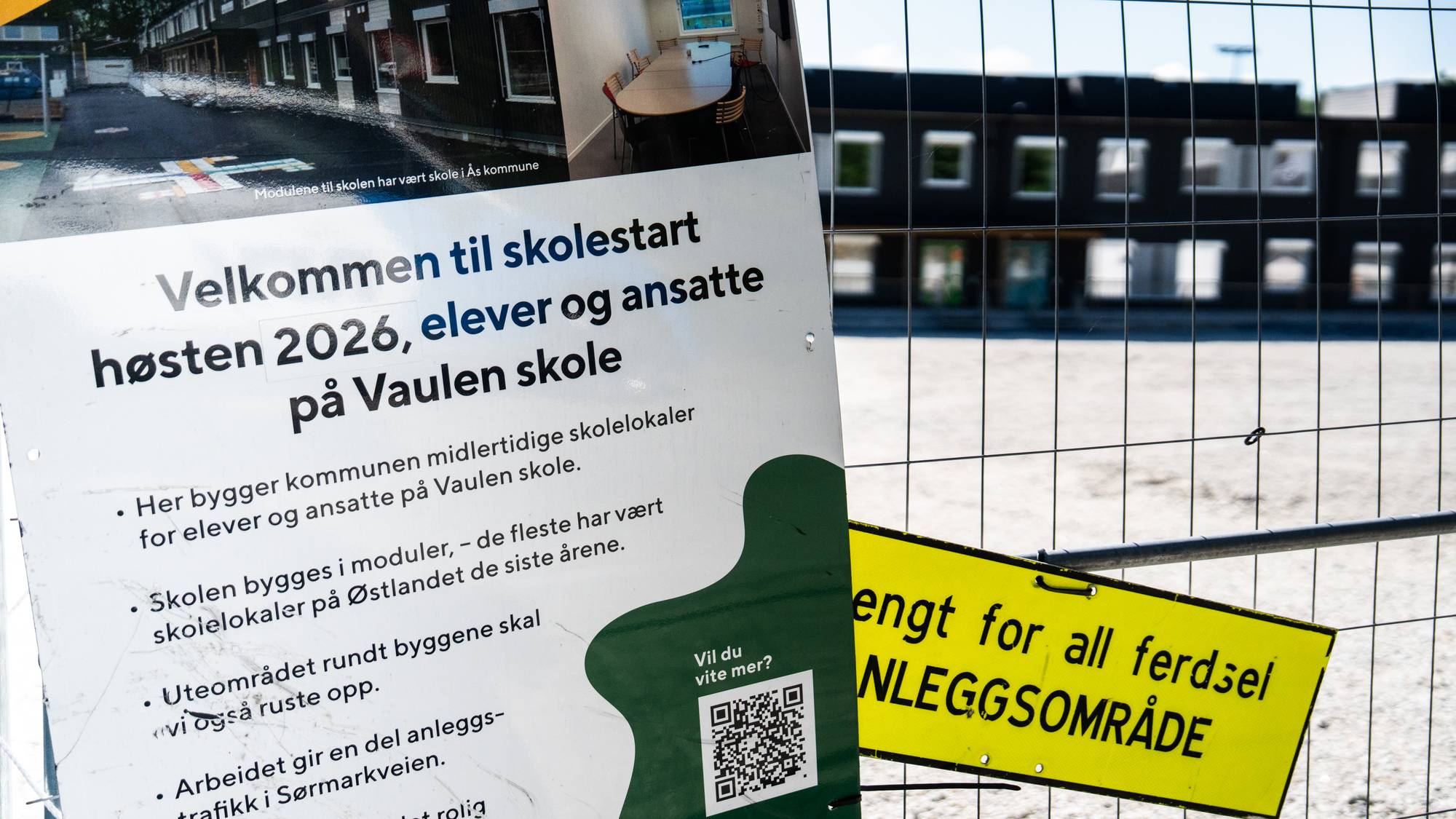 Skole med gjerde og skilt foran
