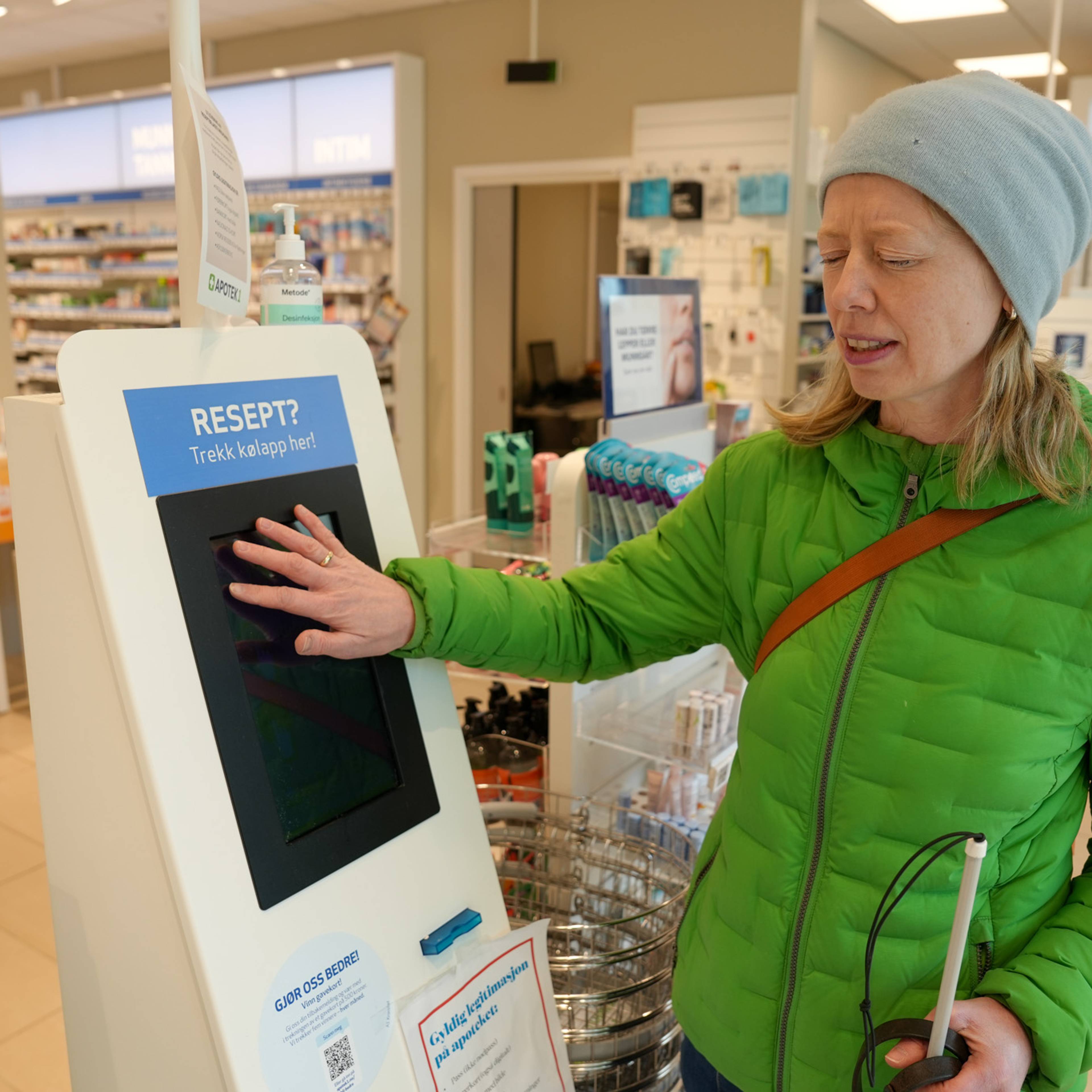 Eva Kirkevik forsøker å trykke på kølapp-automat på apotek for å få ut resept. Automatene har bare touchskjerm og er ikke tilpasset blinde og svaksynte.