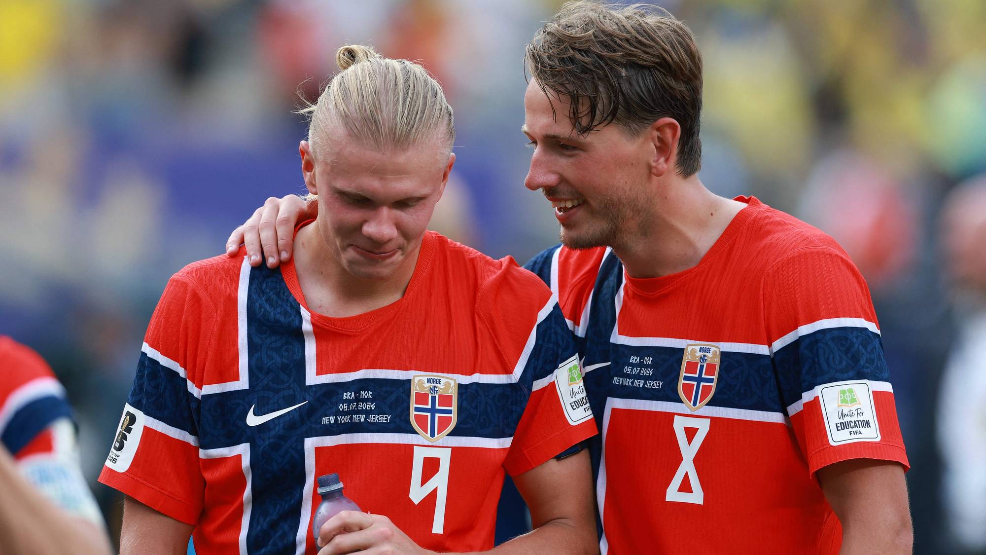 Erling Braut Haaland og en lagkamerat i norske landslagsdrakter på fotballbanen. (Bildebeskrivelsen er laget av en KI-tjeneste)