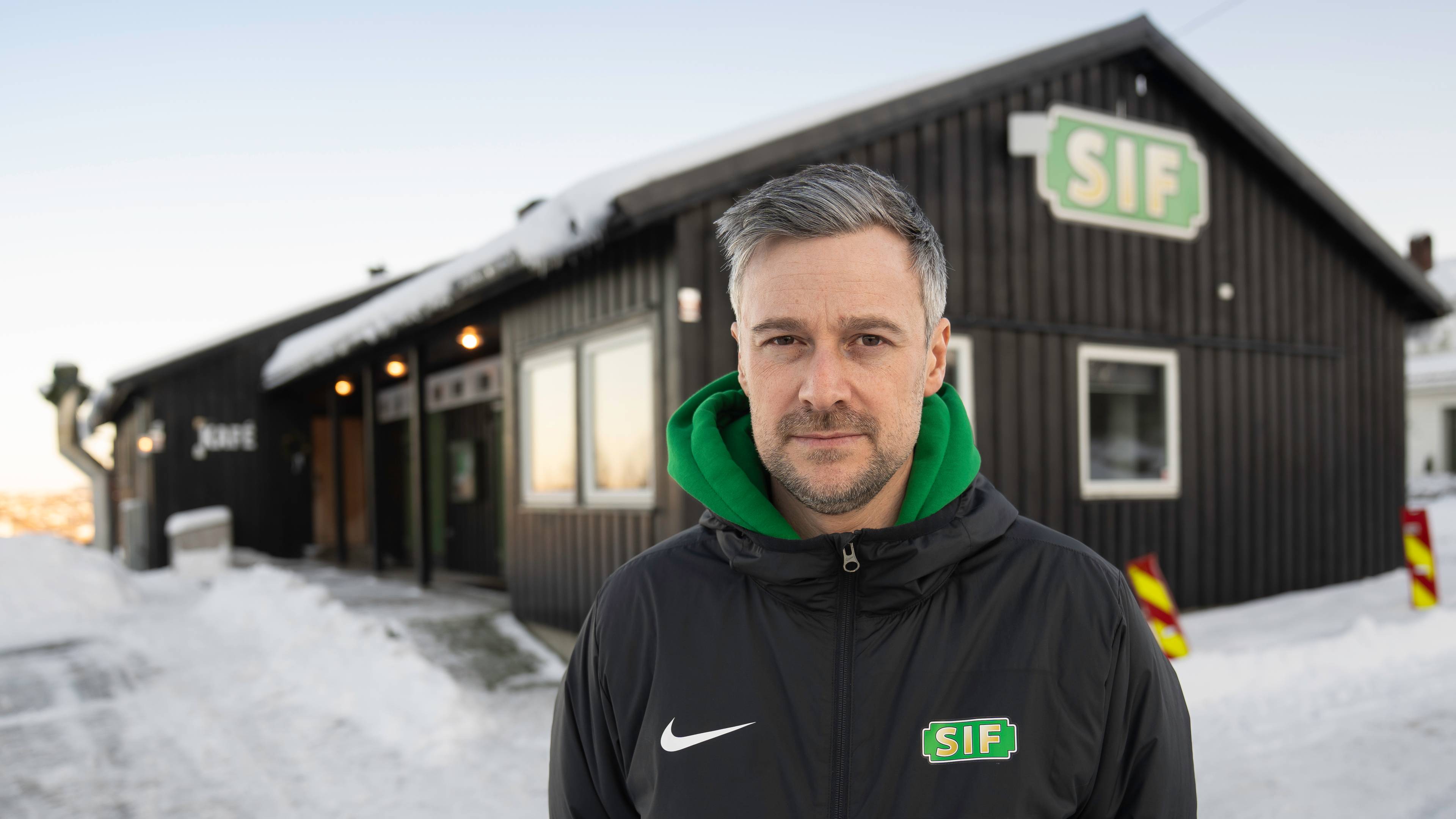 Mann i ytterjakke foran klubbhus